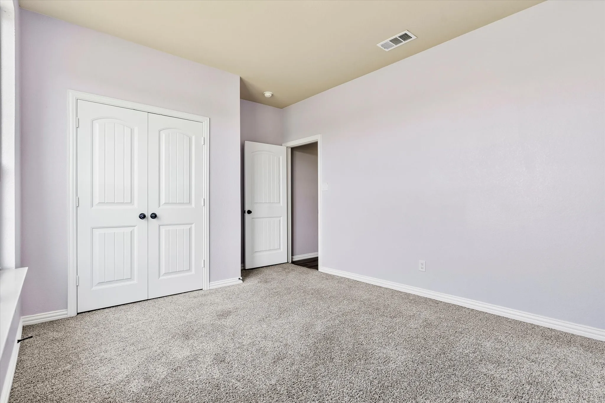 Wall-to-wall carpeting, light-toned walls, white trim, and white paneled doors with dark hardware