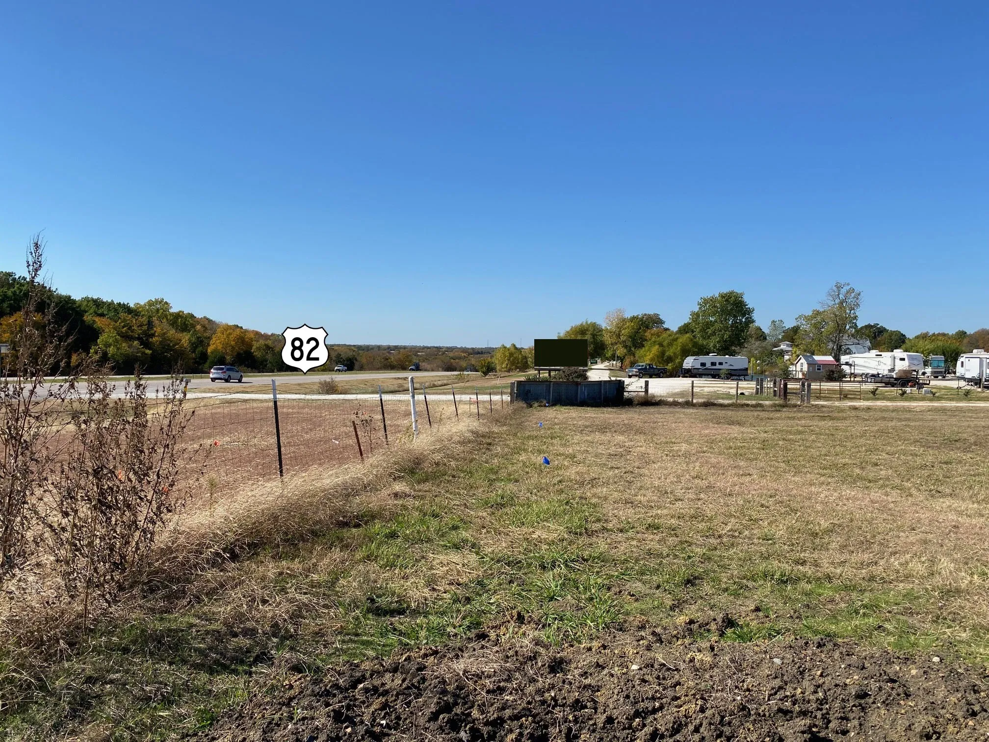 Expansive undeveloped parcel featuring a visible US Route 82 sign and a clear blue sky