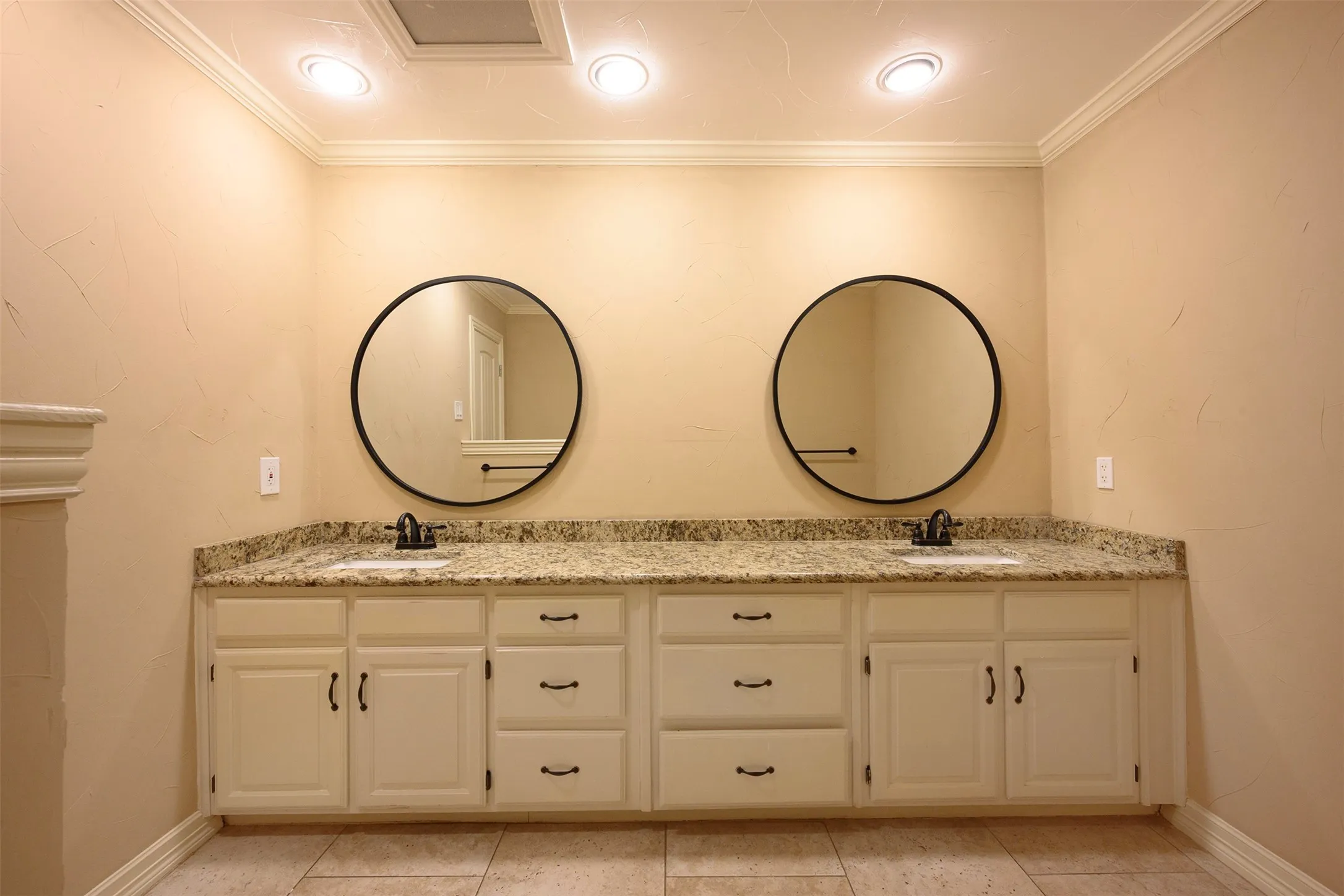 Dual vanity with granite-style countertop, undermount sinks, and black round mirrors