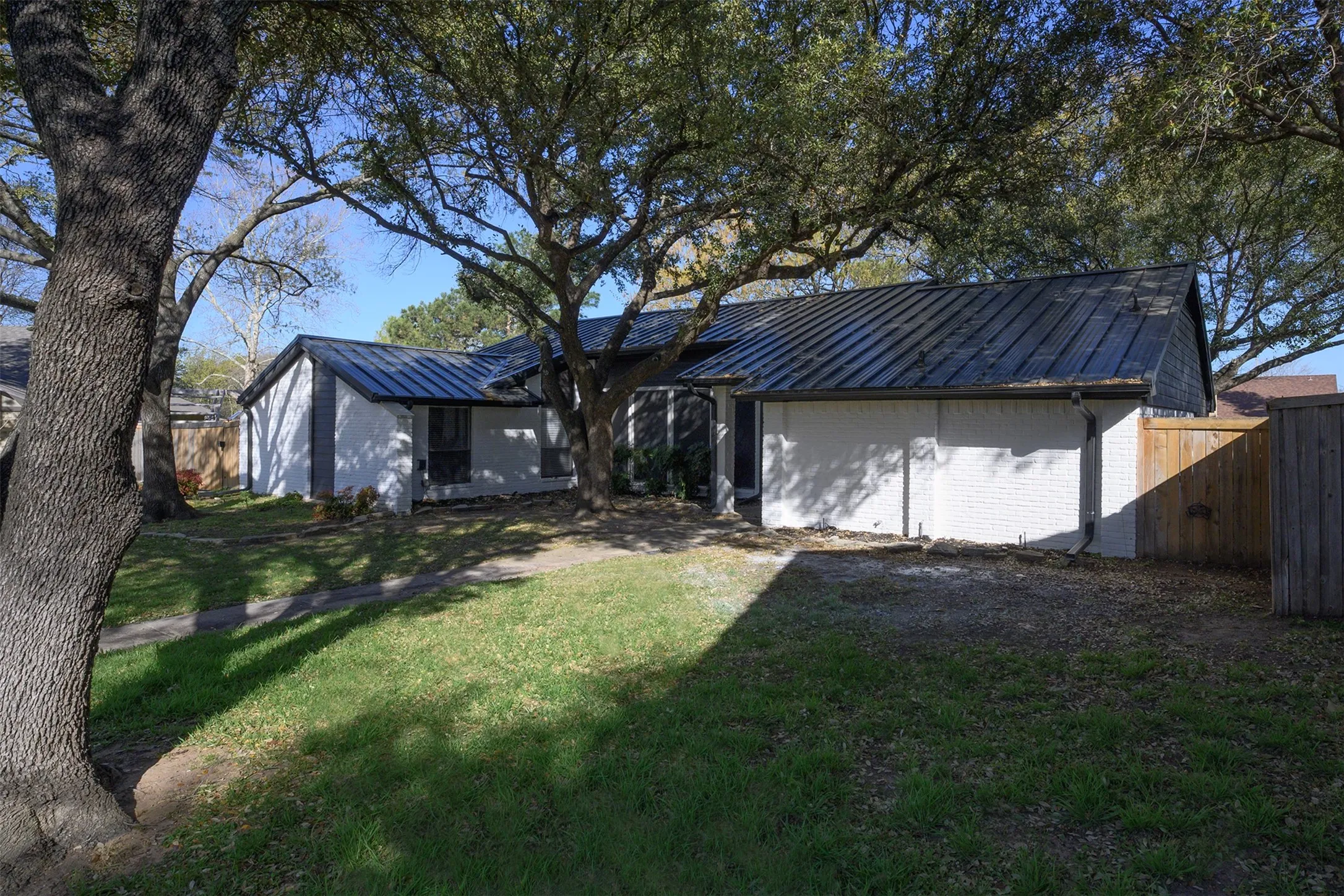 Single-story residence featuring a dark metal roof, white painted brick exterior, and dark trim accents