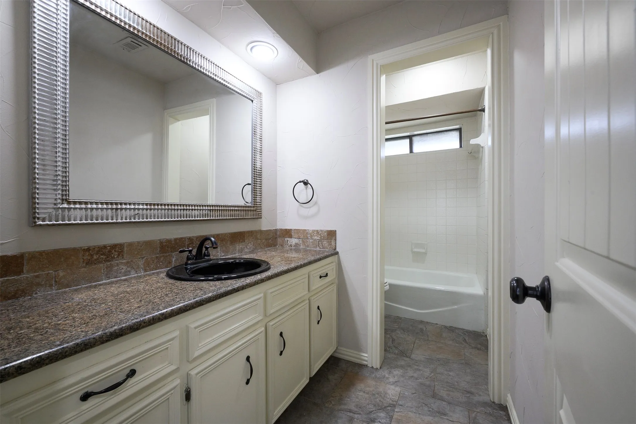 Bathroom featuring a vanity with a dark countertop, white cabinetry, and a large framed mirror
