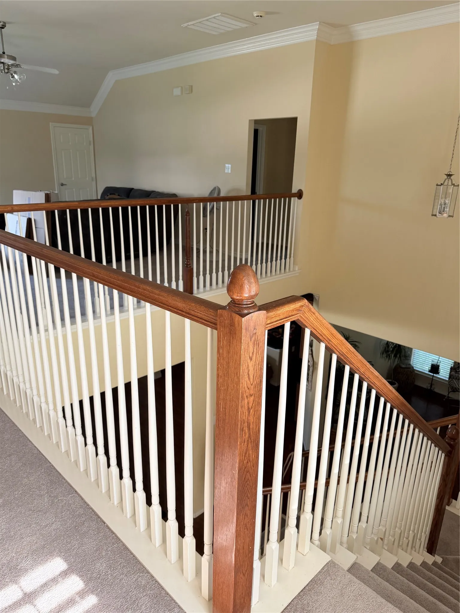 Staircase featuring wood-finish handrails and newel posts with white balusters
