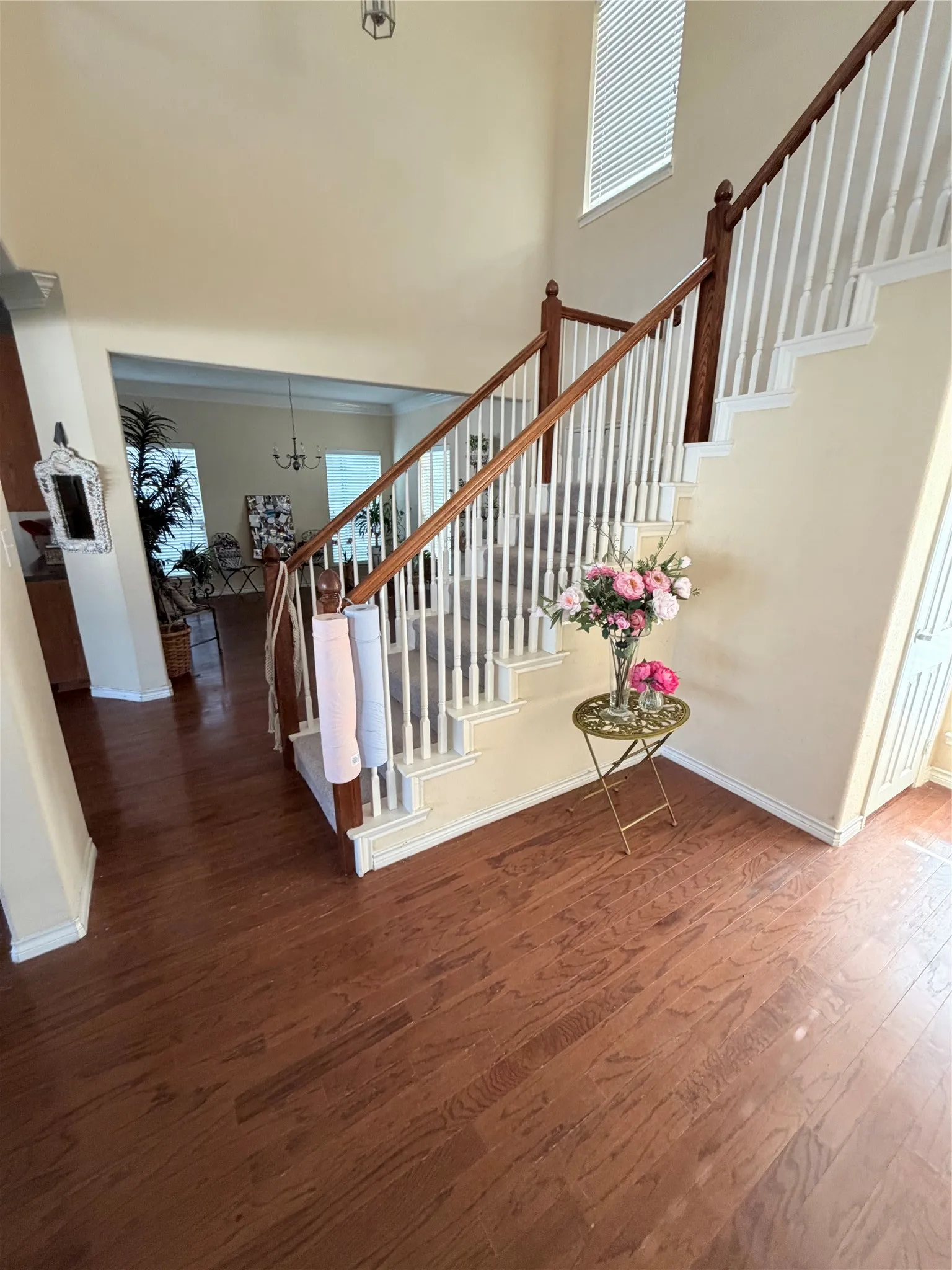 Grand entry featuring rich wood-finish flooring, a double-height ceiling, and a prominent staircase with white balusters and dark wood handrails
