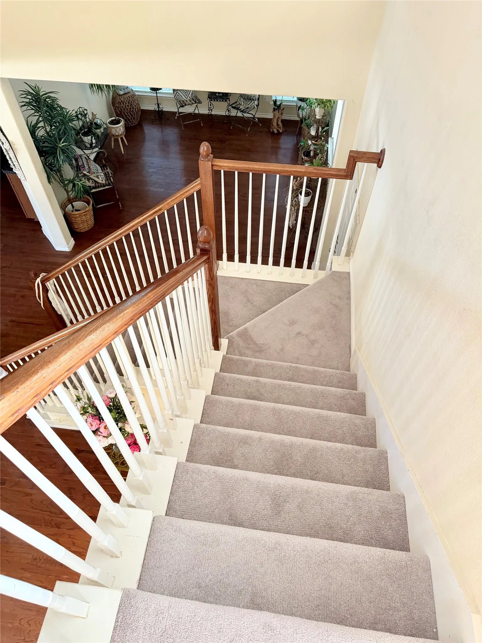 Staircase featuring wood handrails, white balusters, and light gray carpeted steps