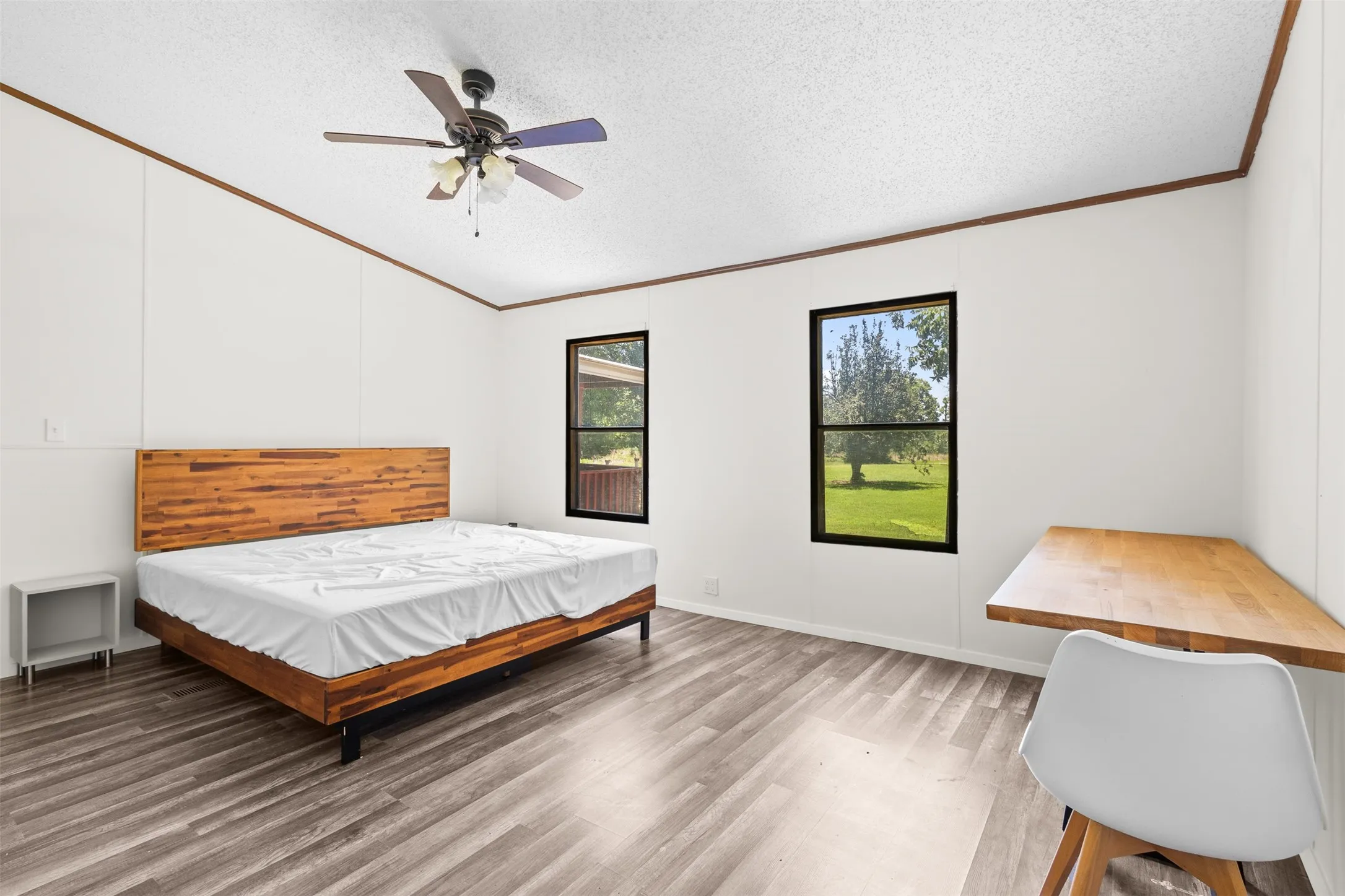 Room featuring wood-finish flooring, white paneled walls, and a ceiling fan with integrated lighting