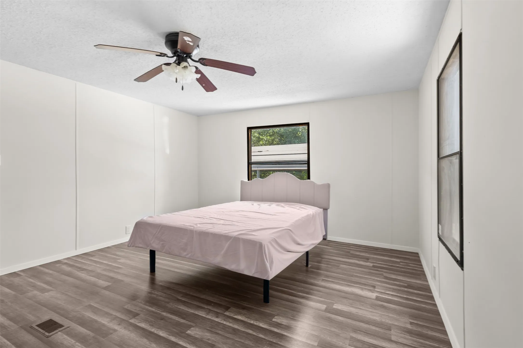 Spacious room with wood-finish flooring, a contemporary ceiling fan, and white paneled walls