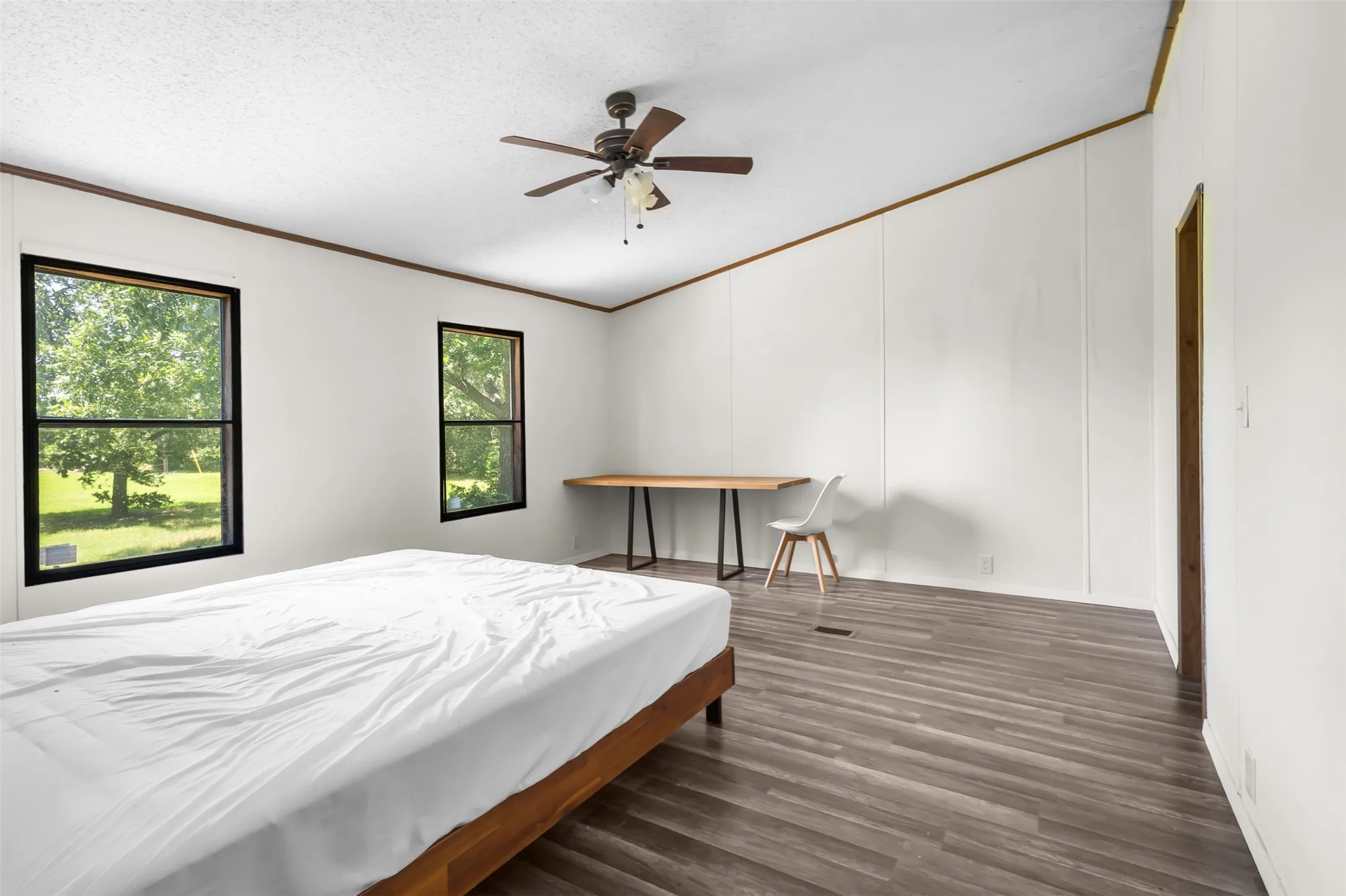 Spacious room featuring wood-finish flooring, white panel walls, and a vaulted ceiling with exposed wood beams