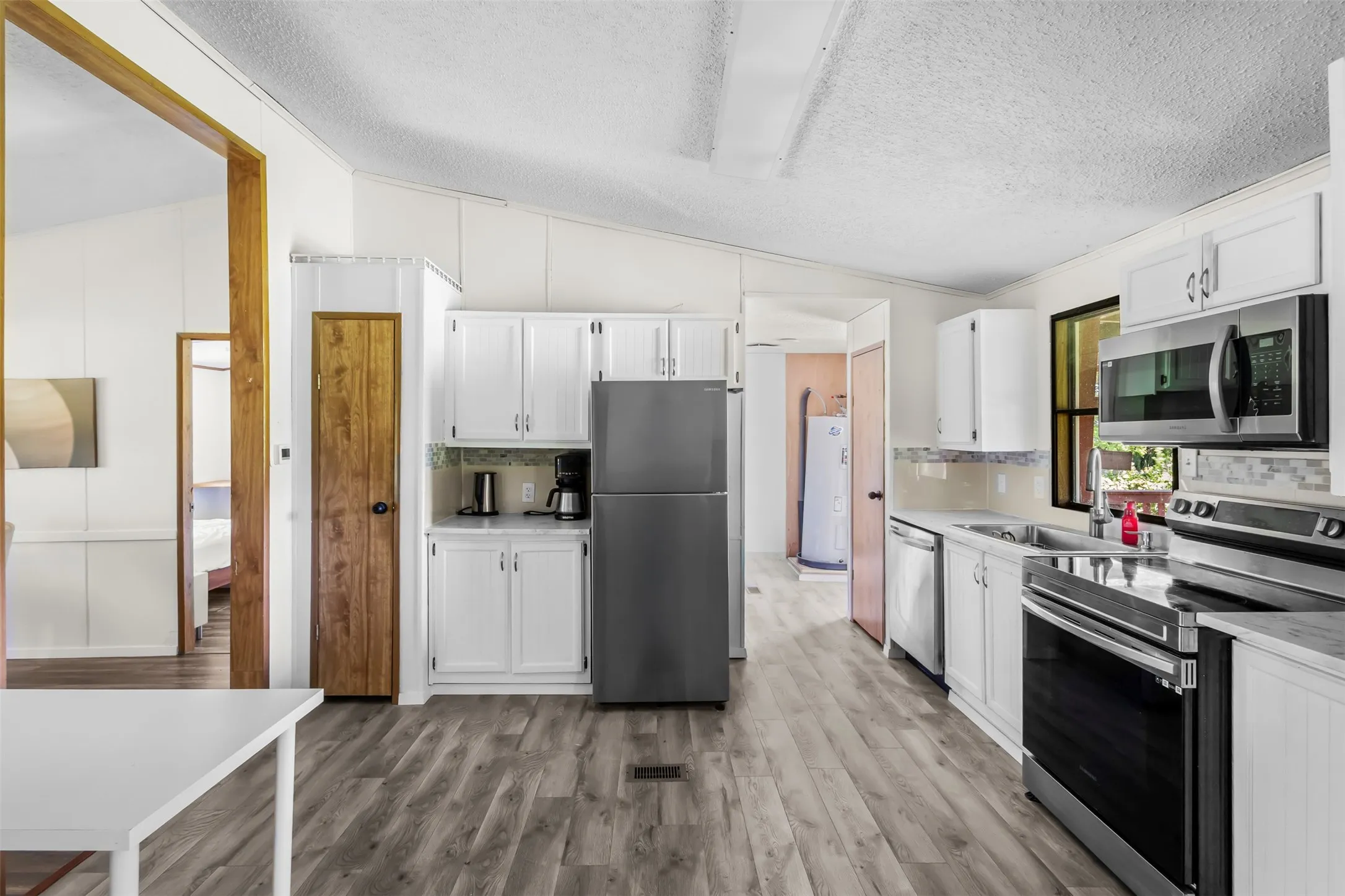 Kitchen featuring wood-finish flooring, white cabinetry, and stainless steel appliances