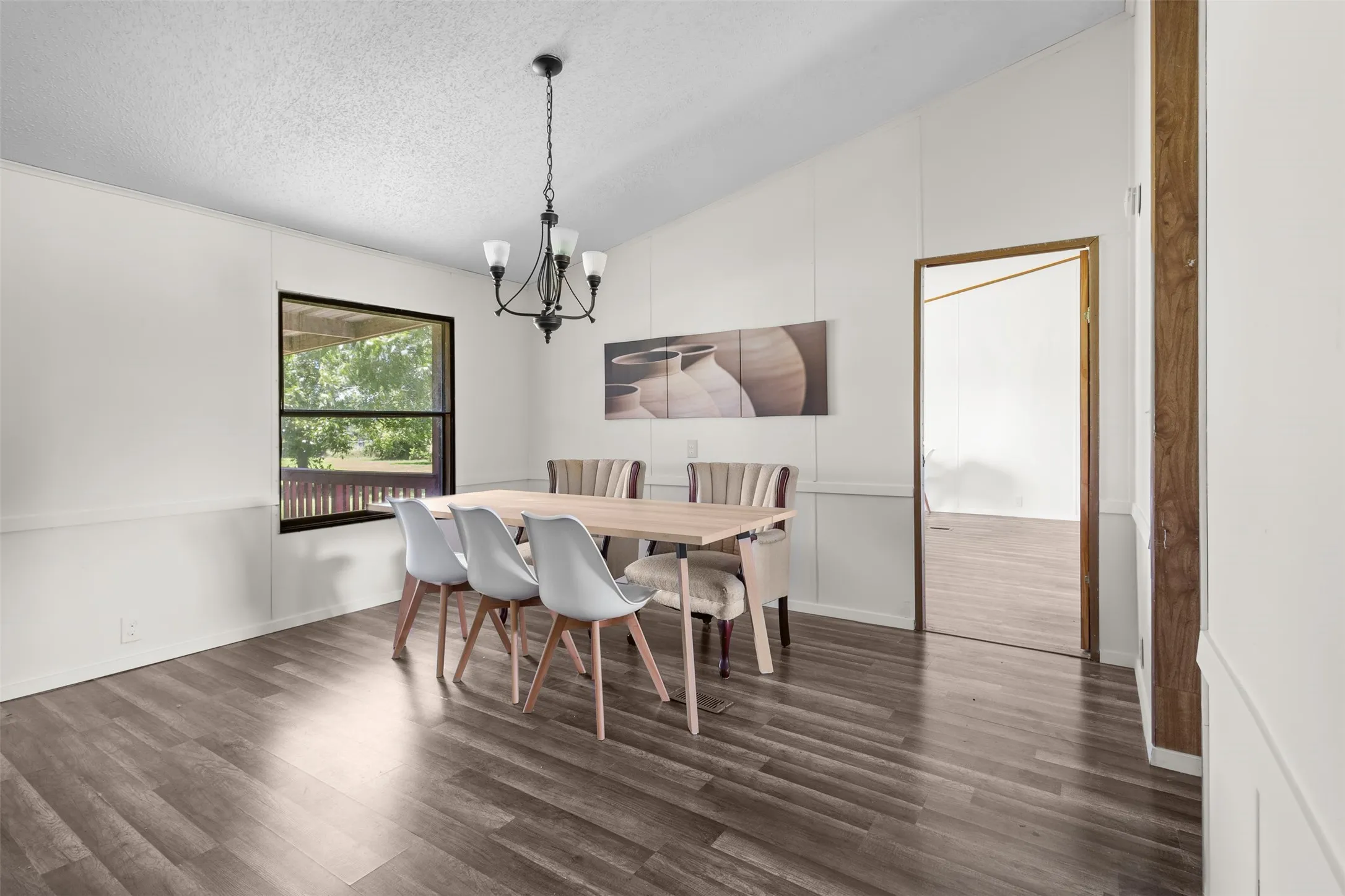 Spacious interior featuring wood-finish flooring, a vaulted ceiling, and a black chandelier