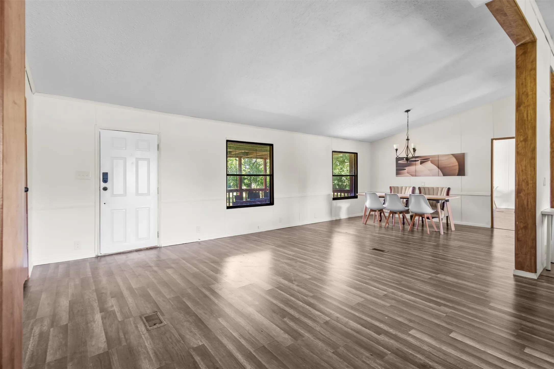 Open-concept interior featuring wood-finish flooring, vaulted ceilings, and white paneled walls