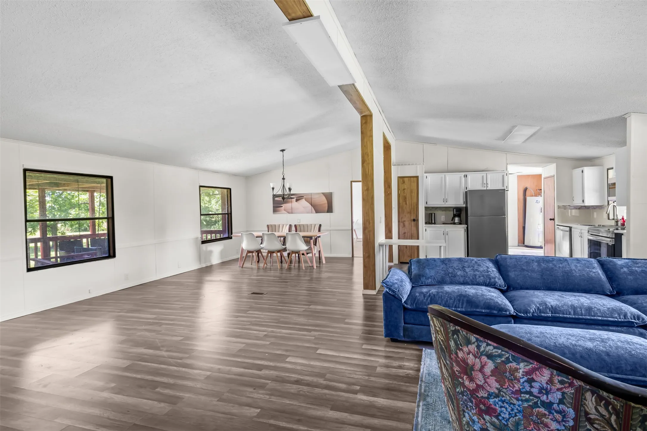 Spacious interior with wood-finish flooring, white walls, and exposed wood structural beams