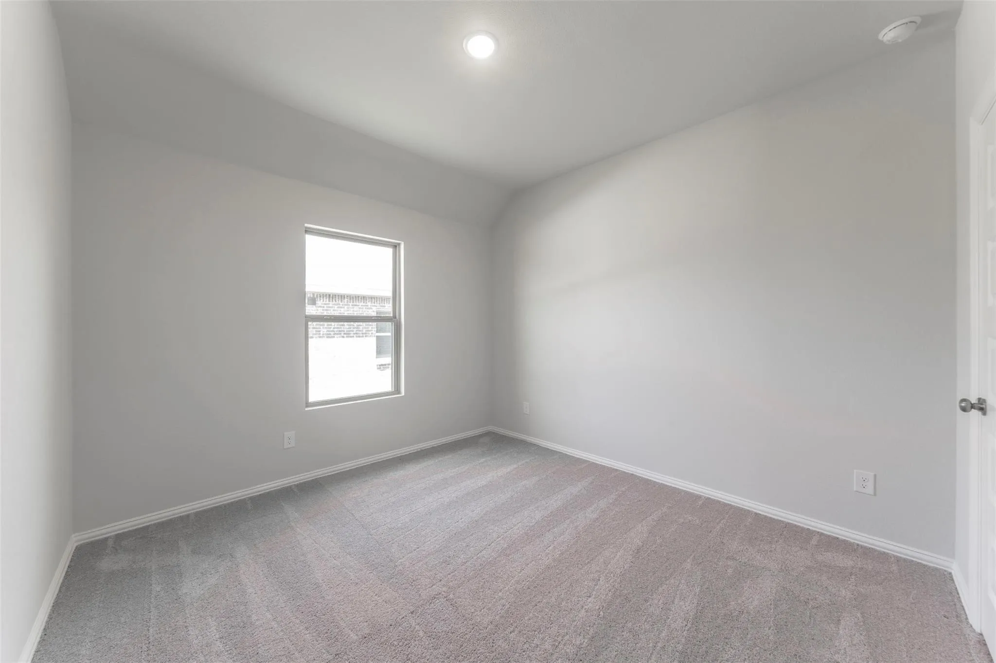Room featuring light gray walls, gray patterned carpeting, and a single window with white trim