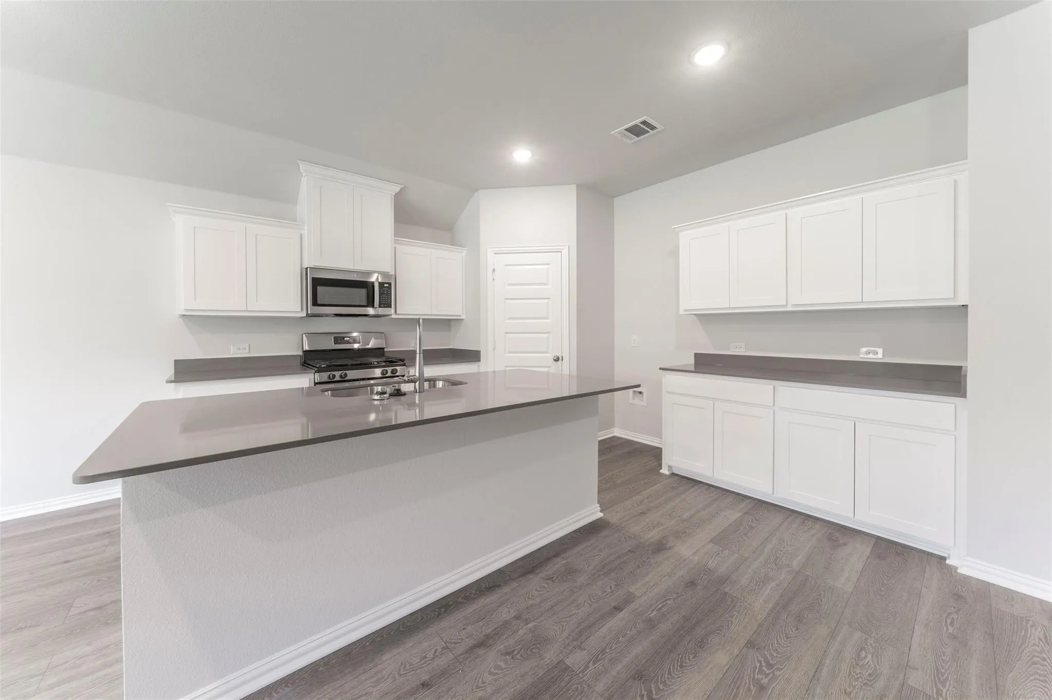 Kitchen with a large island featuring a stainless steel sink and gooseneck faucet