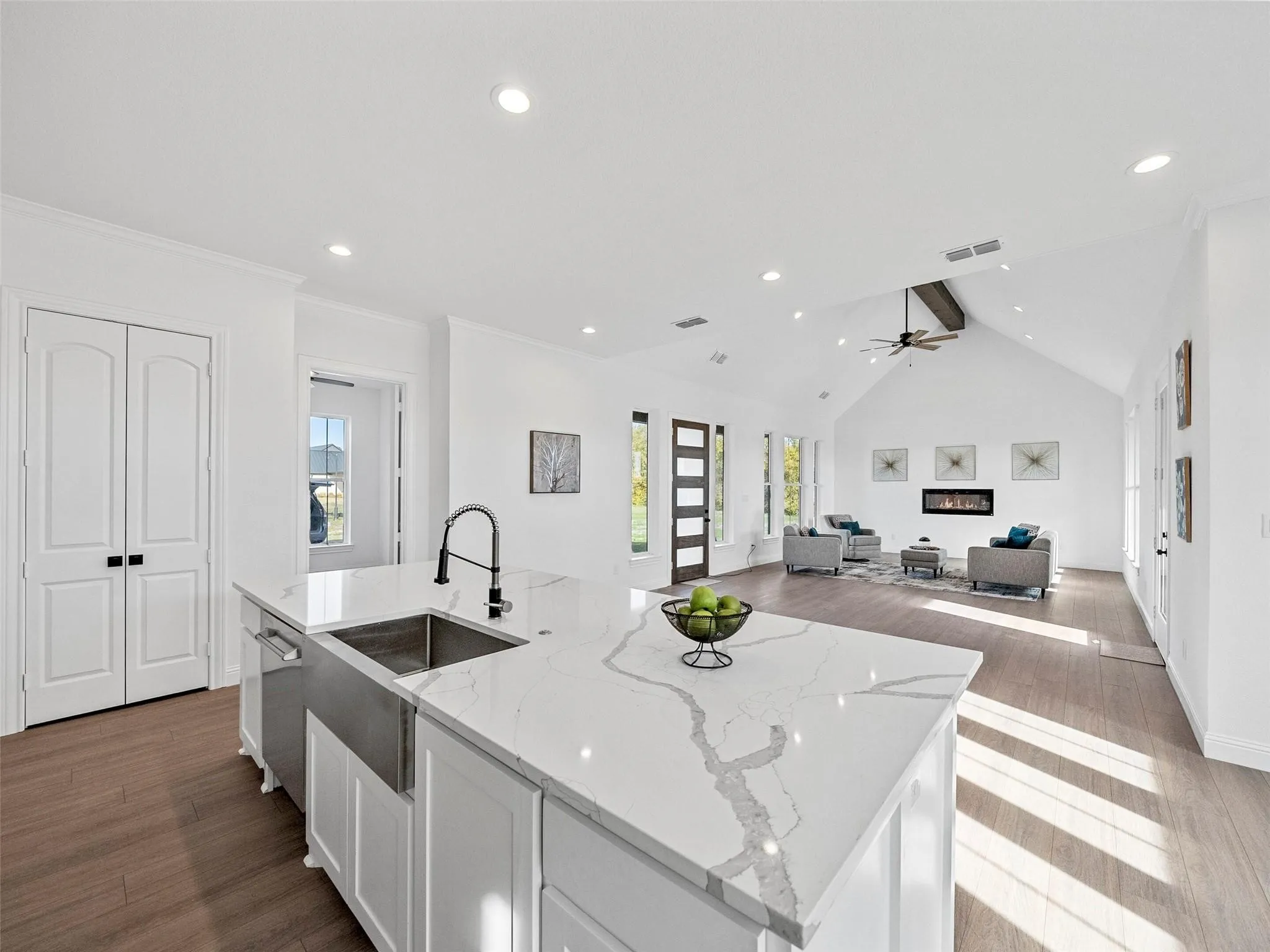 Kitchen island with a stainless steel farmhouse sink, quartz countertop, and dark-finish pull-down faucet