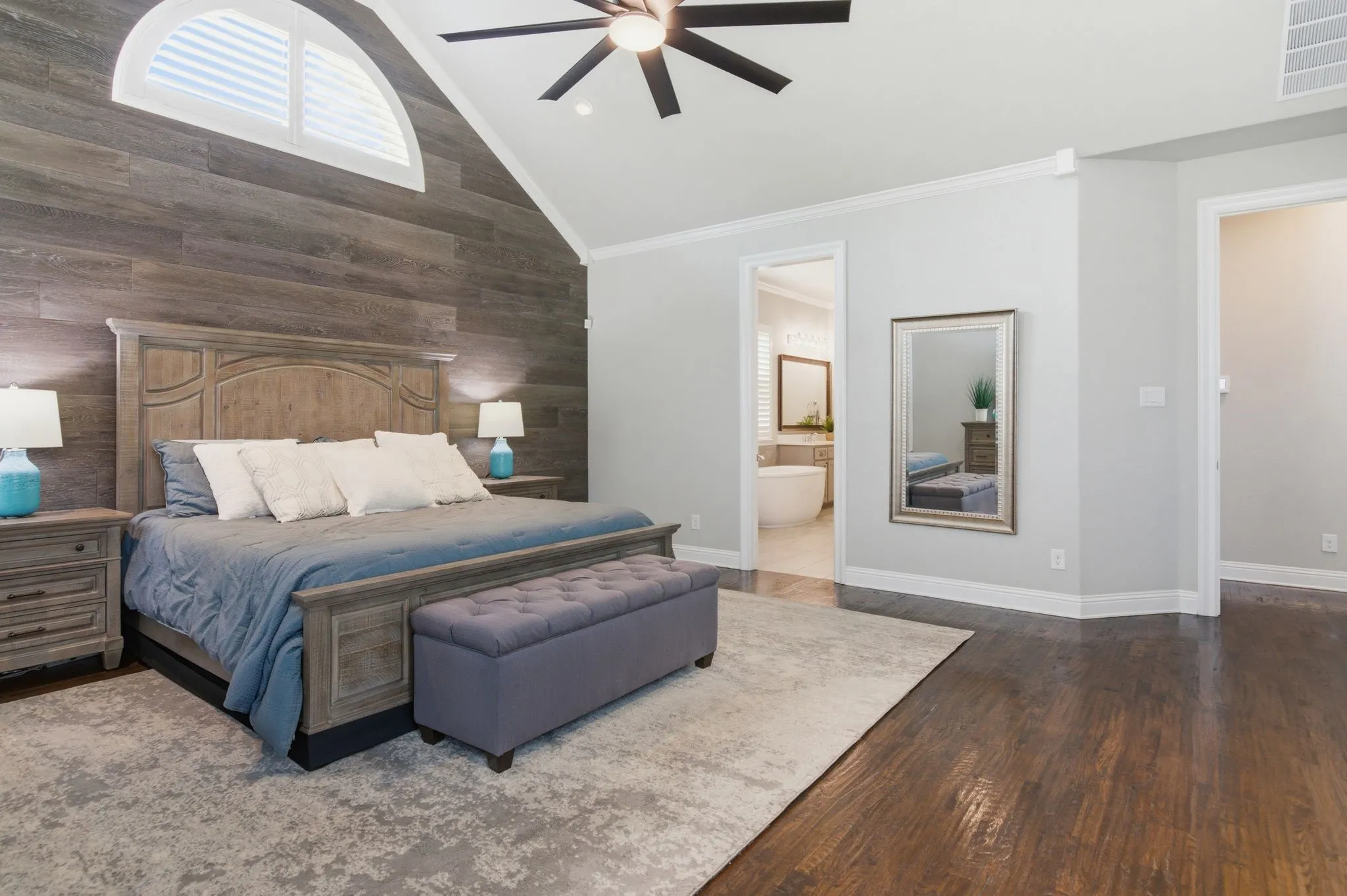 Vaulted ceiling room featuring wood-finish accent wall, dark wood-finish flooring, and a ceiling fan