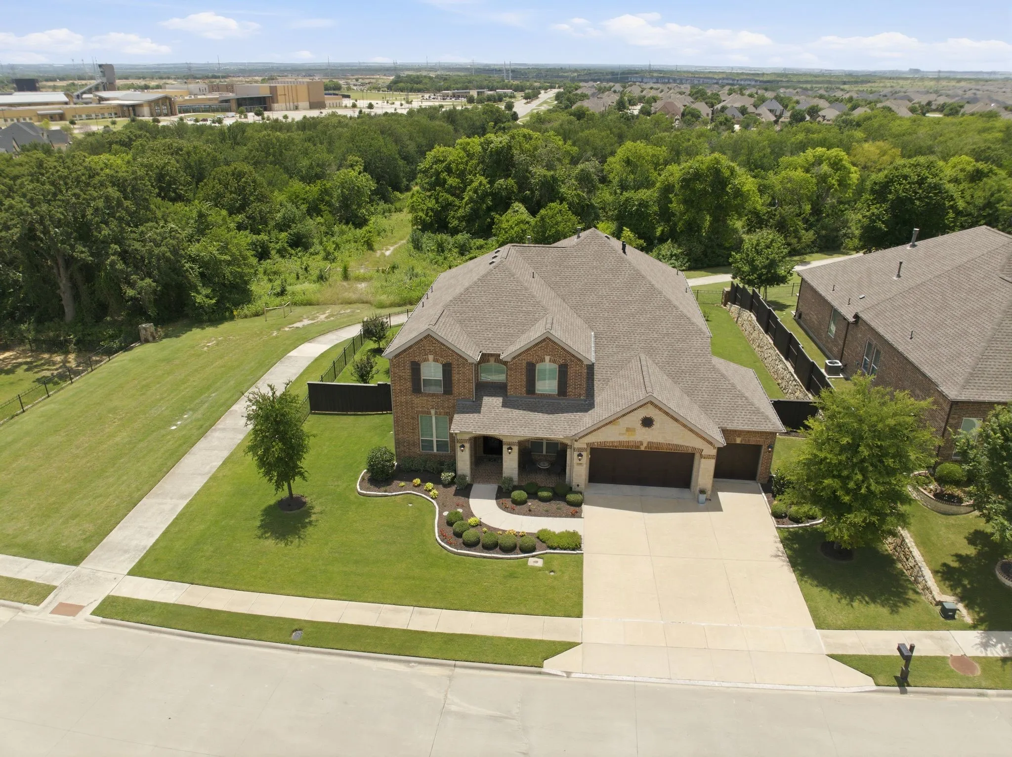 Two-story brick and stone facade residence featuring a two-car garage, concrete driveway, and established landscaping