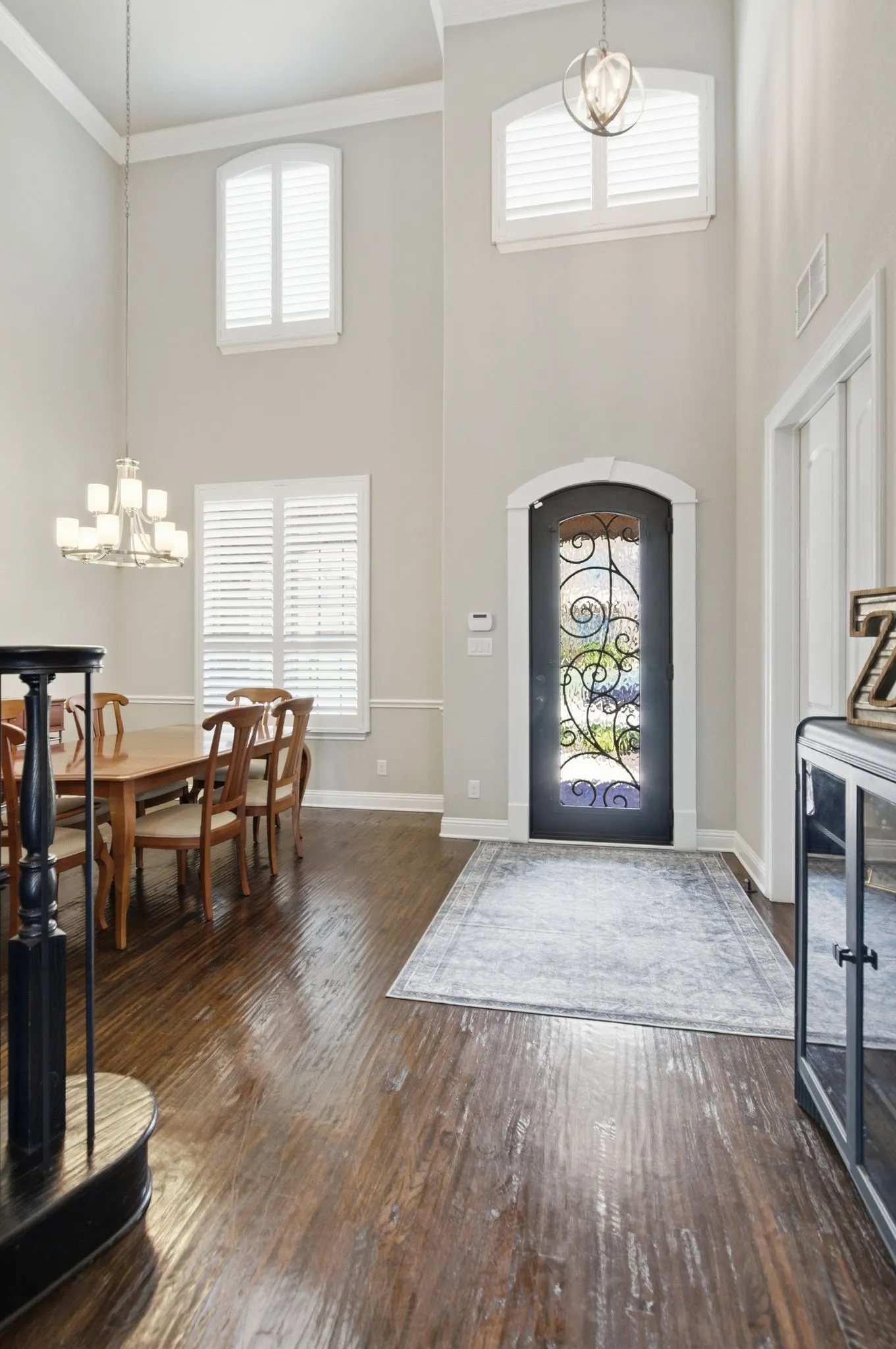 Two-story foyer with rich wood-finish flooring extending into the dining space