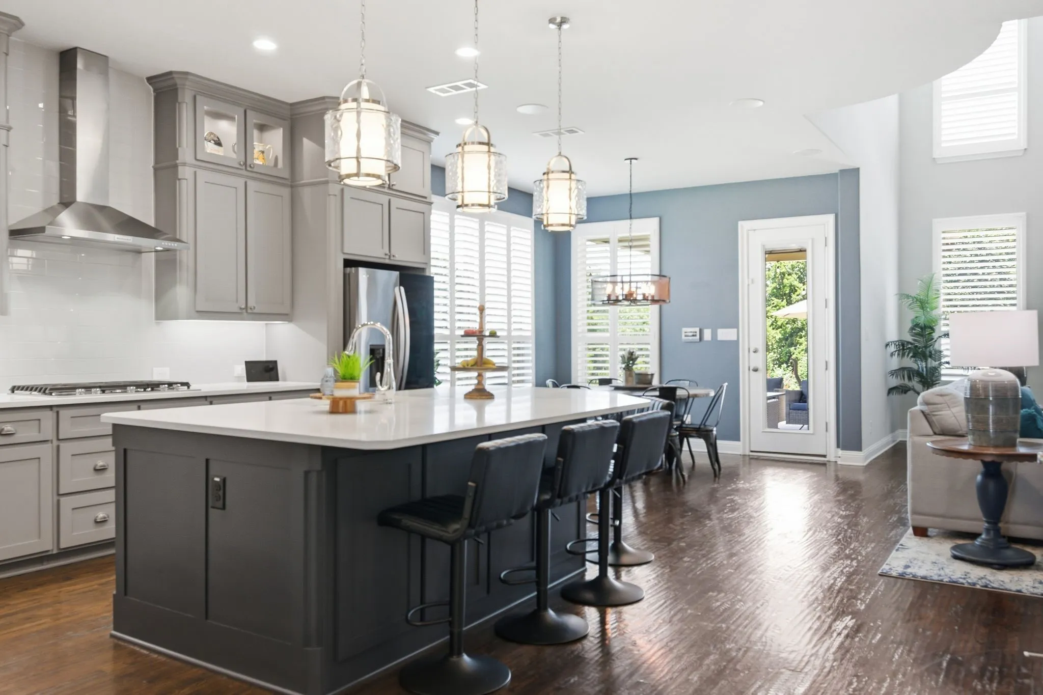Spacious open-concept kitchen featuring a large island with seating, grey cabinetry, stainless steel appliances, and a white subway tile backsplash