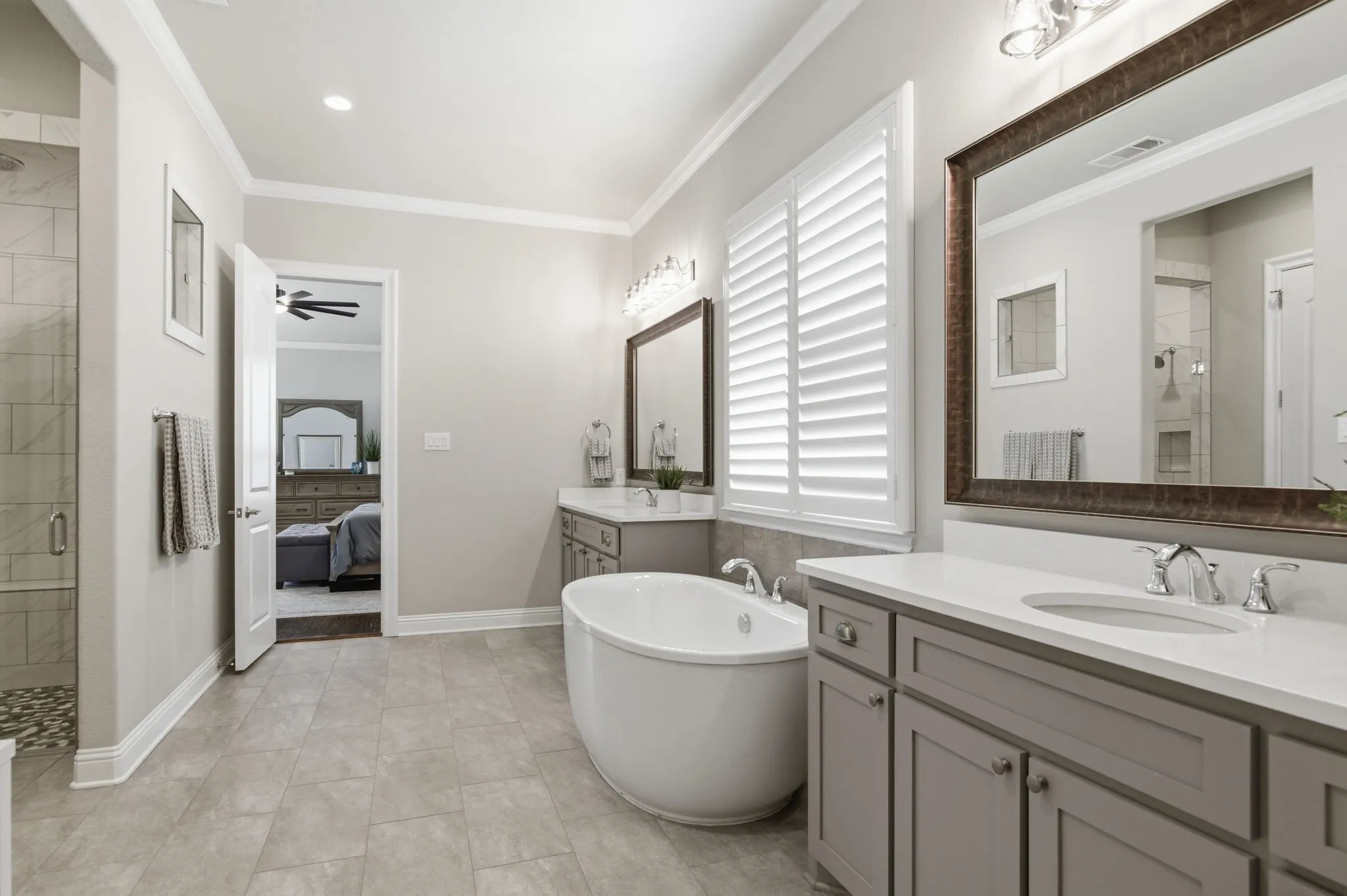 Spacious bathroom featuring a freestanding soaking tub, dual vanity with white countertops, and a glass-enclosed shower with tiled walls and a pebble floor