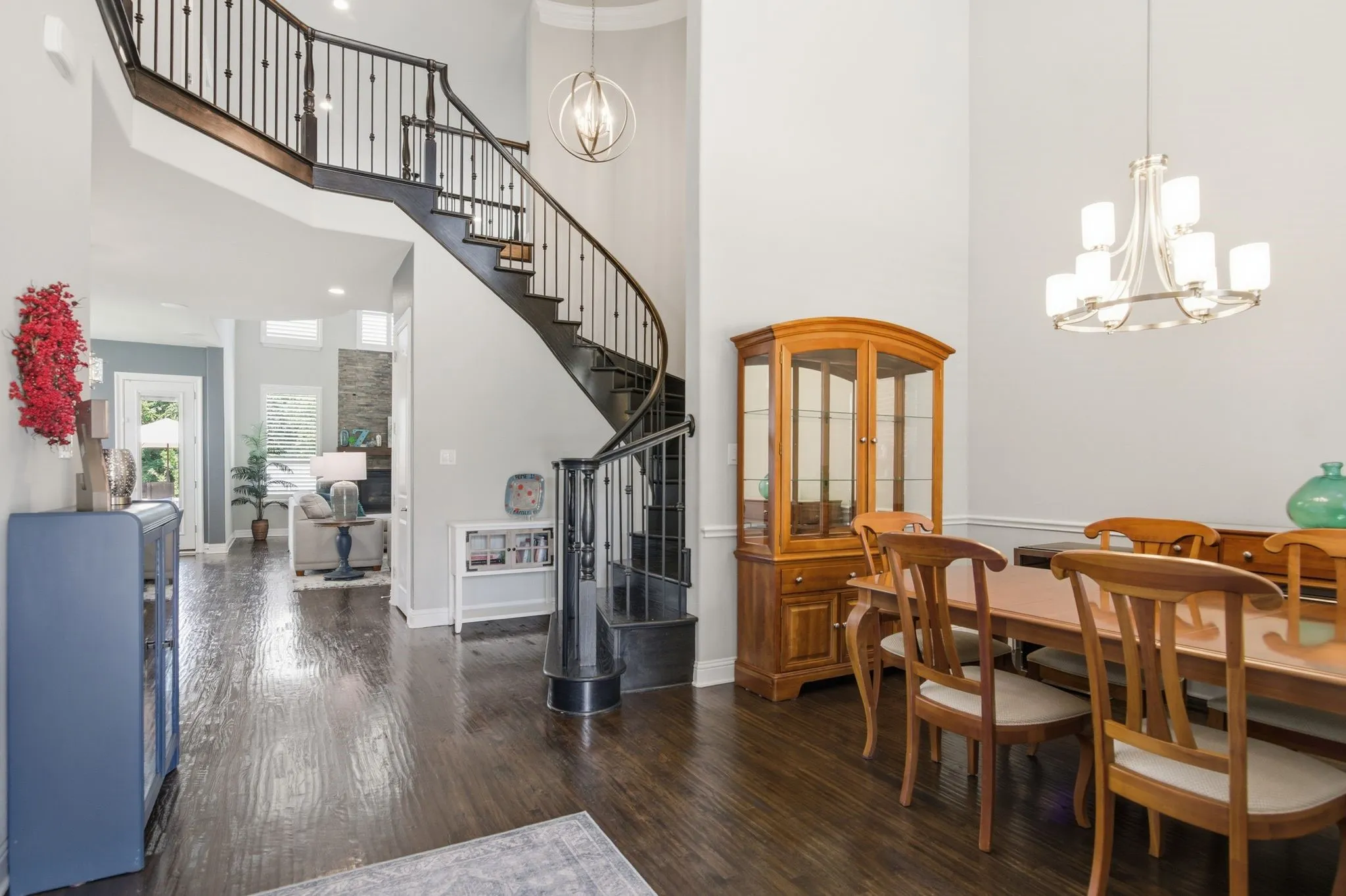 Grand foyer with a curved staircase featuring dark wood treads and wrought iron balusters
