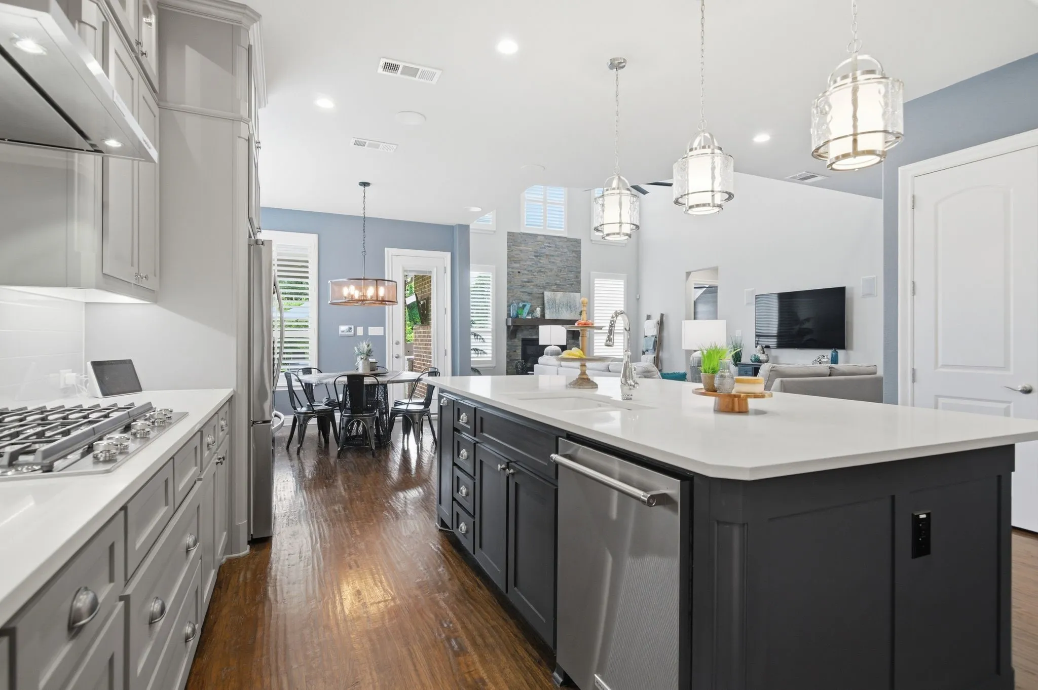 Kitchen featuring a central island with an undermount sink, three pendant lights, and integrated stainless steel dishwasher