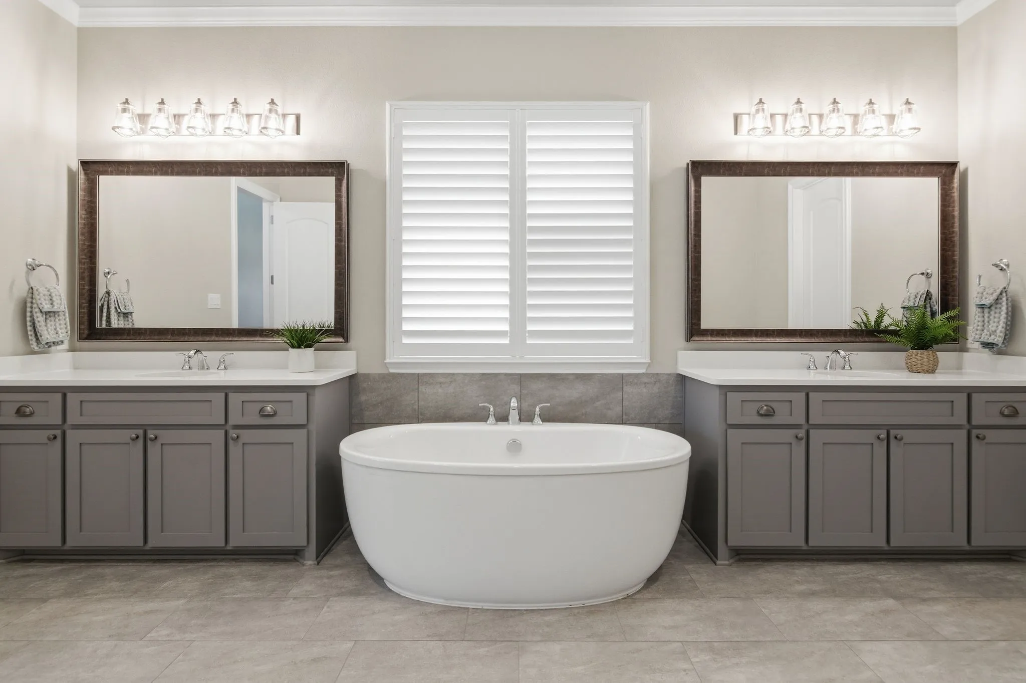 Freestanding soaking tub centered between dual vanities