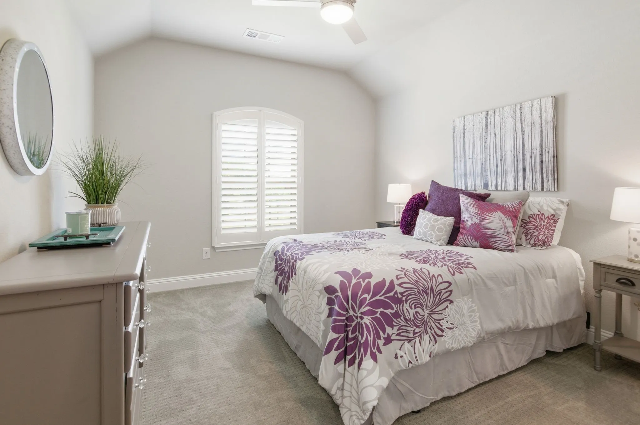 Vaulted ceiling bedroom featuring an arched window with plantation shutters, ceiling fan, and neutral carpeting