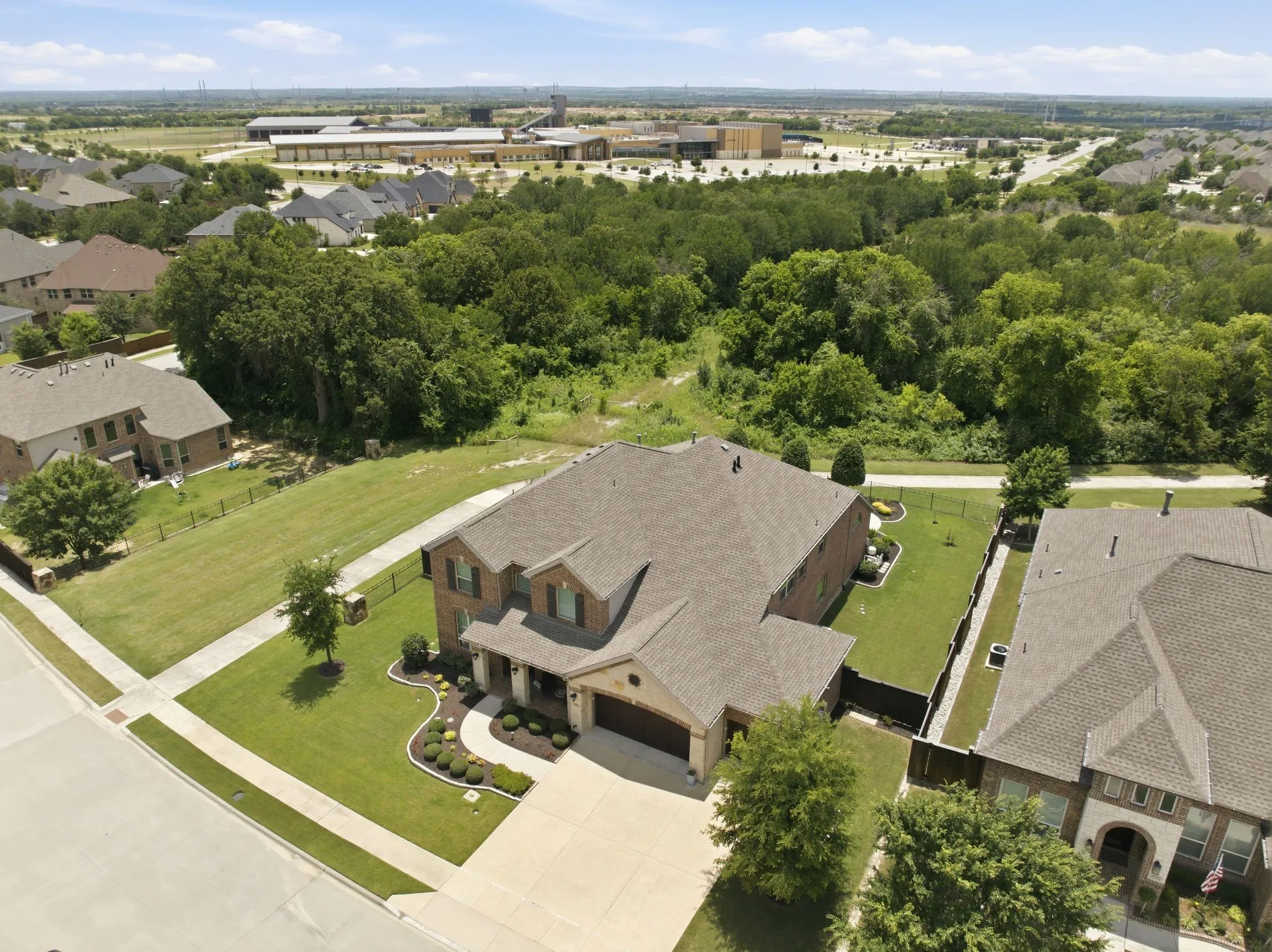 Brick and stone facade residence with a multi-gabled roofline, front-facing two-car garage, and a landscaped front yard