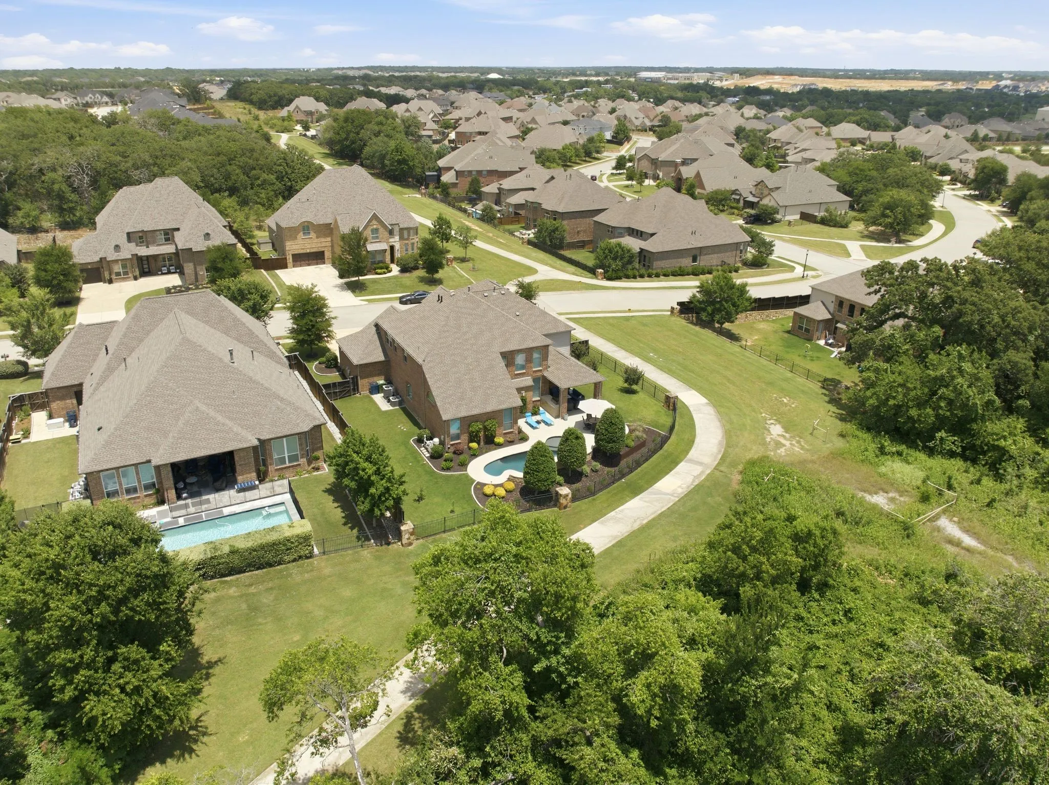 Aerial view of a residential community with multiple houses featuring brick exteriors, pitched roofs, and landscaped yards