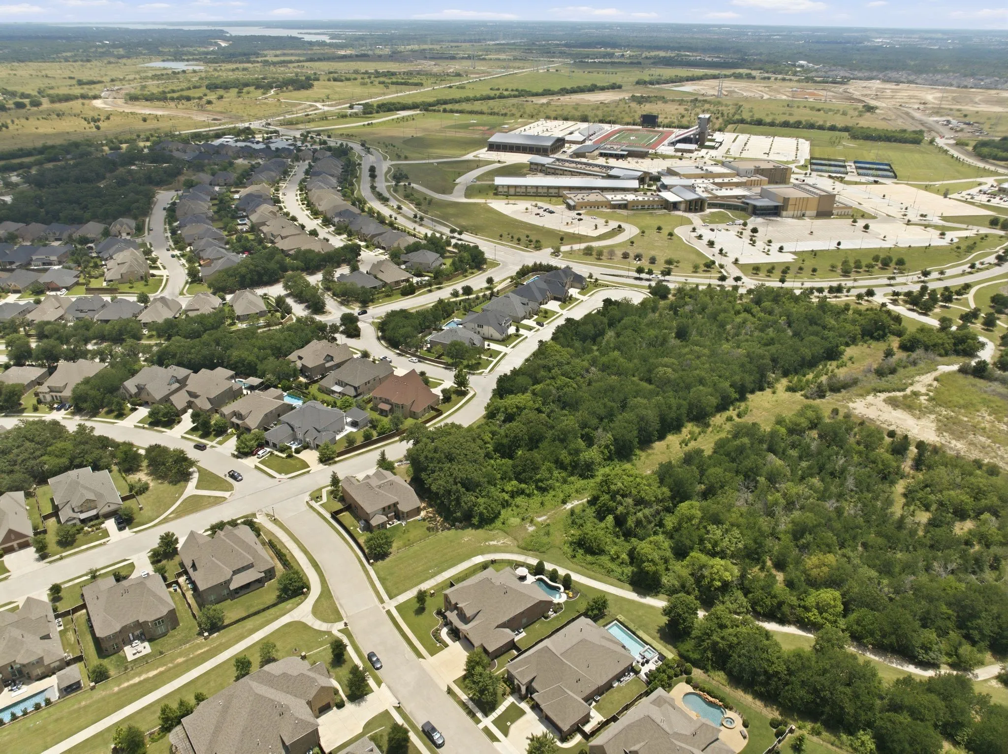 Aerial perspective showcasing a residential community with numerous single-family homes, several featuring private swimming pools