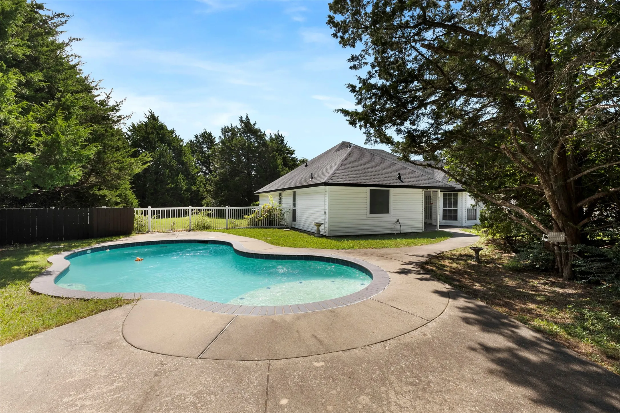 Kidney-shaped inground pool with concrete surround