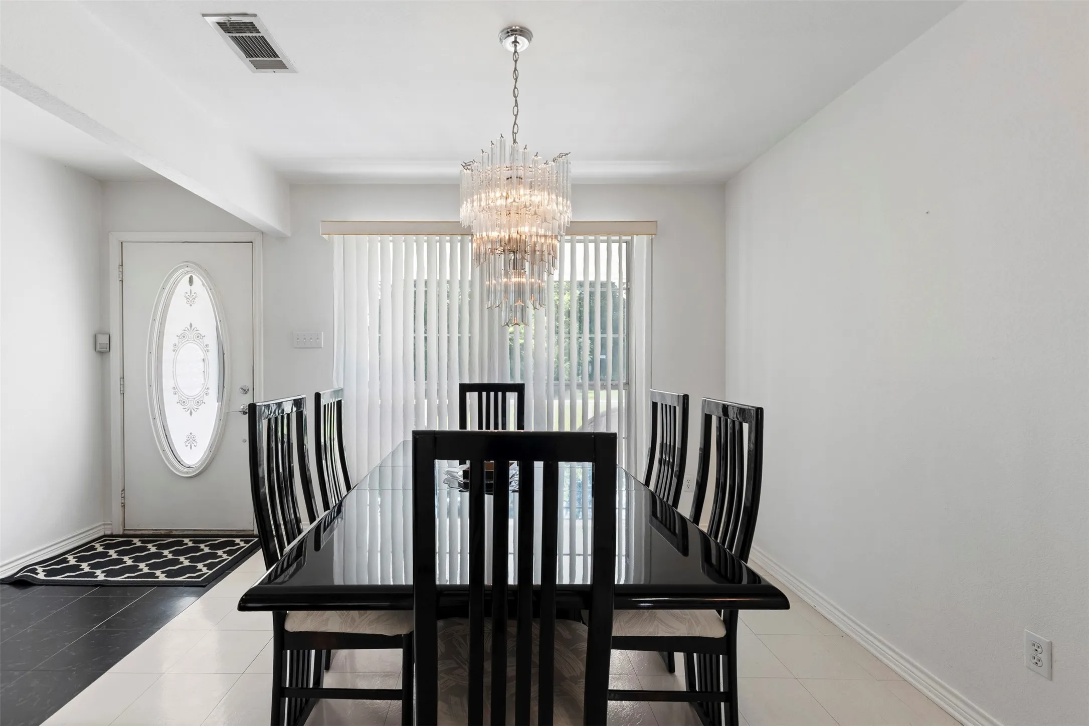 Formal dining space featuring a polished black table and a multi-tiered crystal chandelier