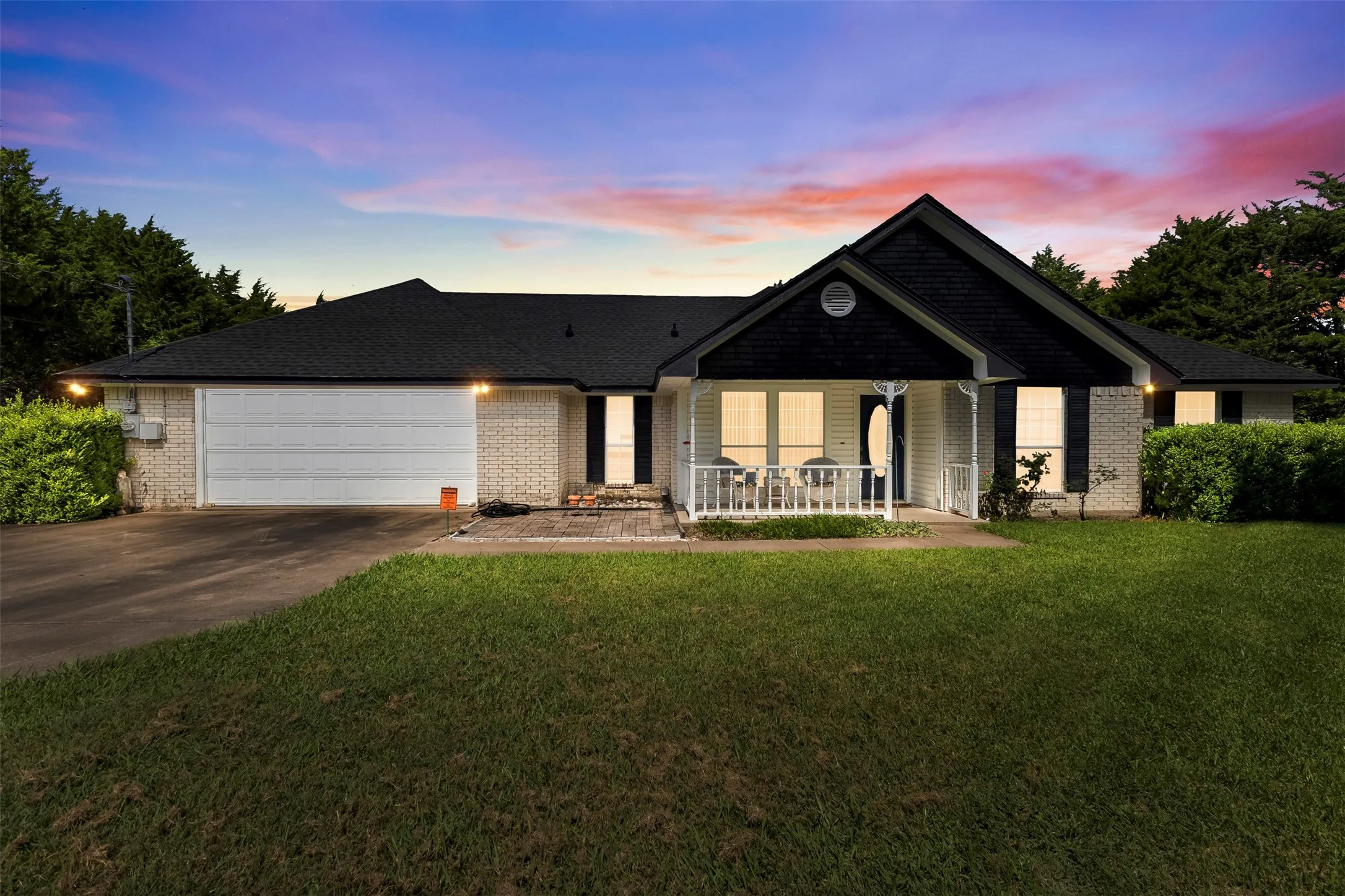 Single-story residence featuring a brick and siding exterior, a prominent gabled entry with a covered porch, an attached two-car garage, and a paved driveway