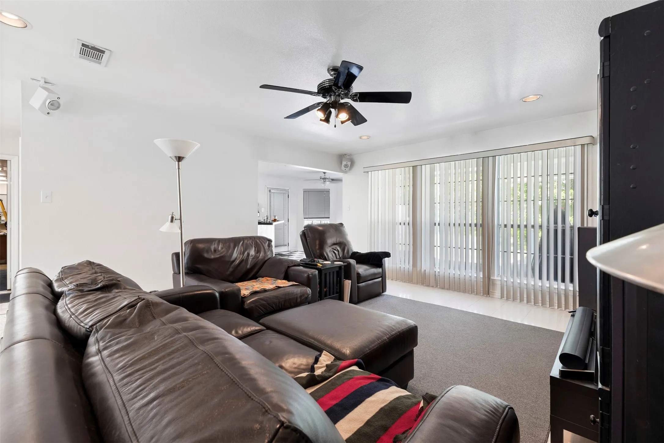 Living area featuring a ceiling fan with integrated lighting, recessed lighting, and wall-mounted speakers