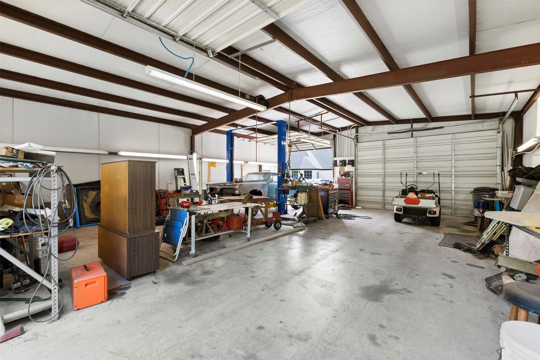 34x40 Spacious metal-frame building featuring a concrete floor, high ceilings with exposed beams, and multiple roll-up doors