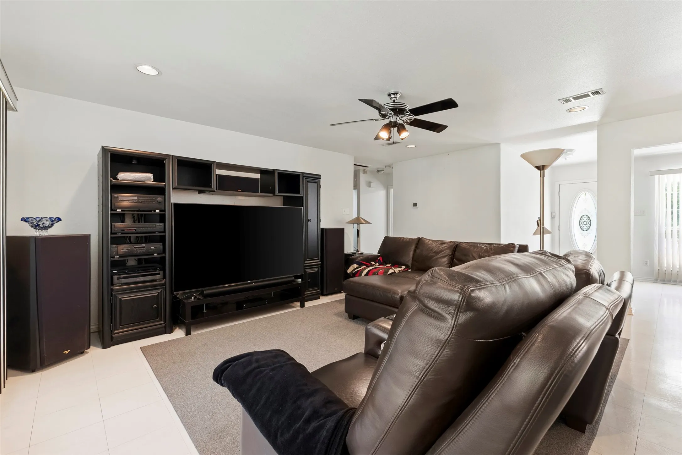 Living area with a large media center featuring built-in shelving and cabinetry, recessed lighting, and a ceiling fan