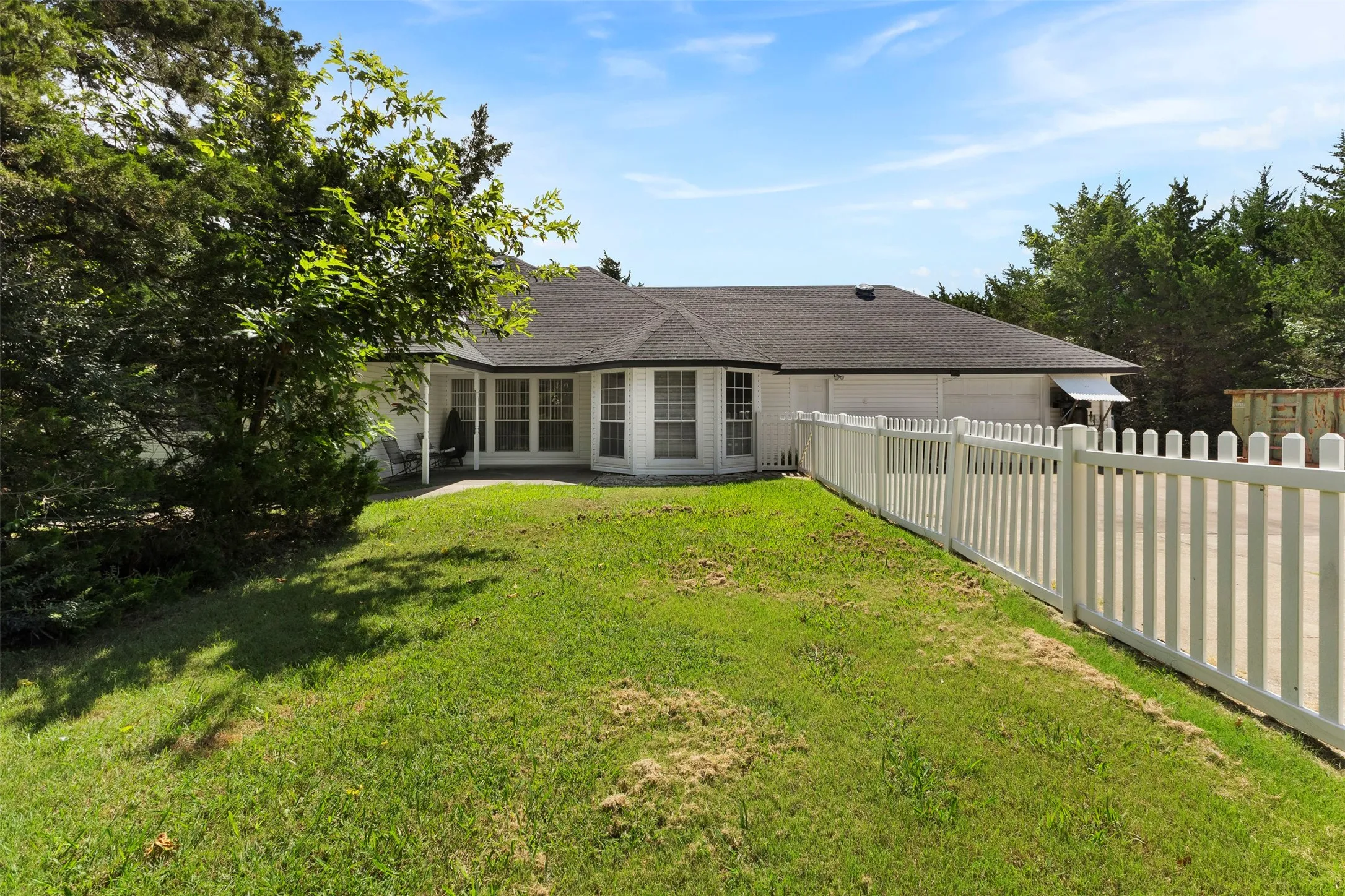 White exterior with bay windows and a dark shingle roof