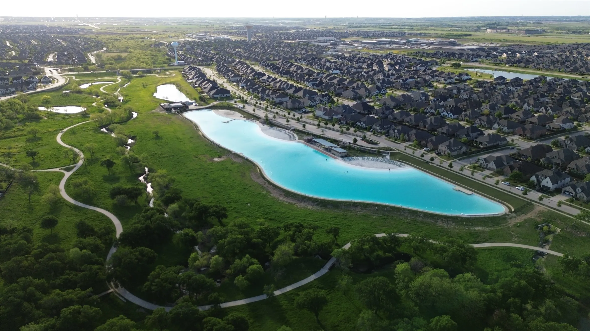 Expansive aerial view showcasing a large, vibrant blue lagoon bordered by residential properties