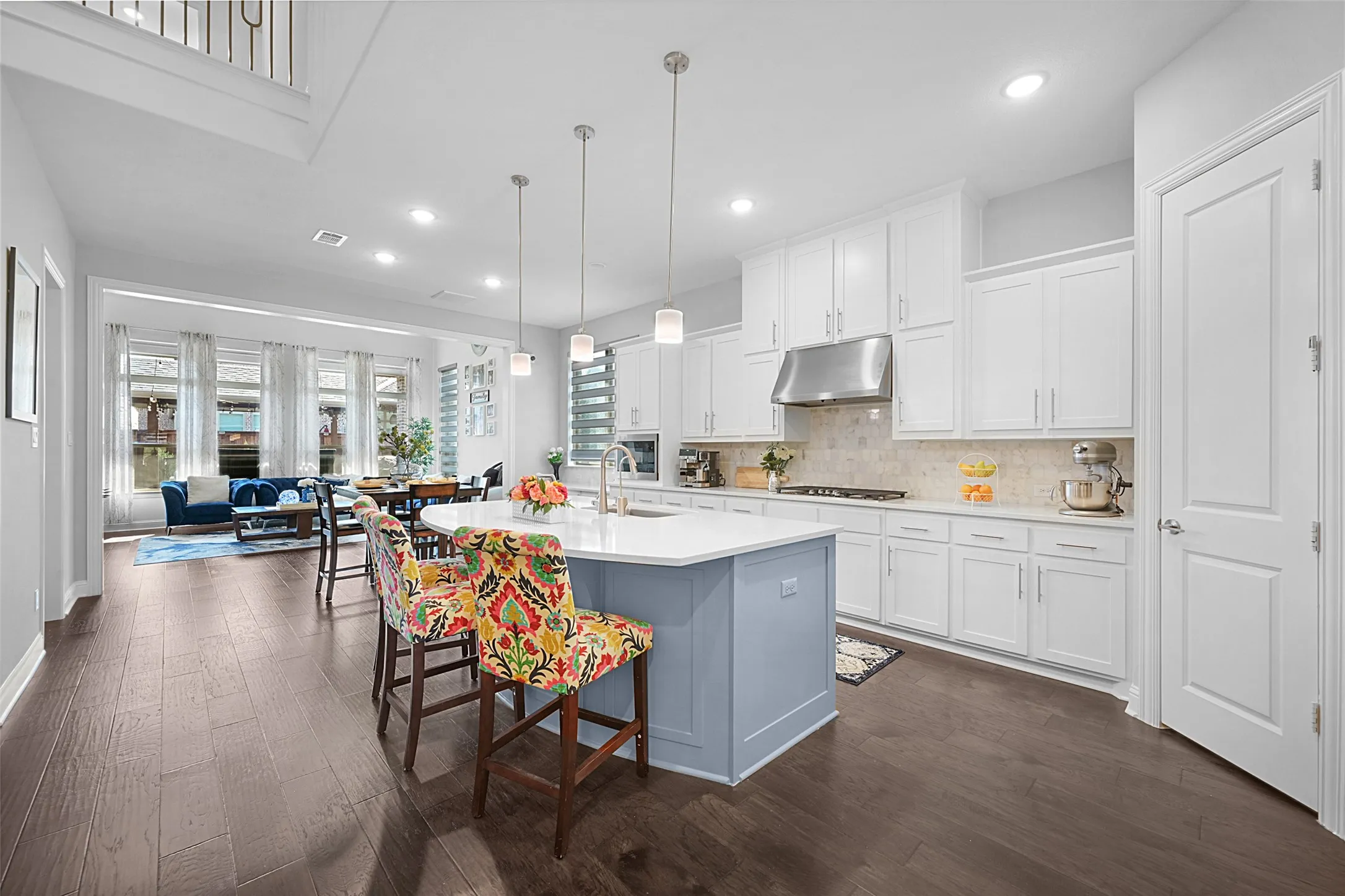 Modern kitchen featuring a light blue island with a white countertop and pendant lighting