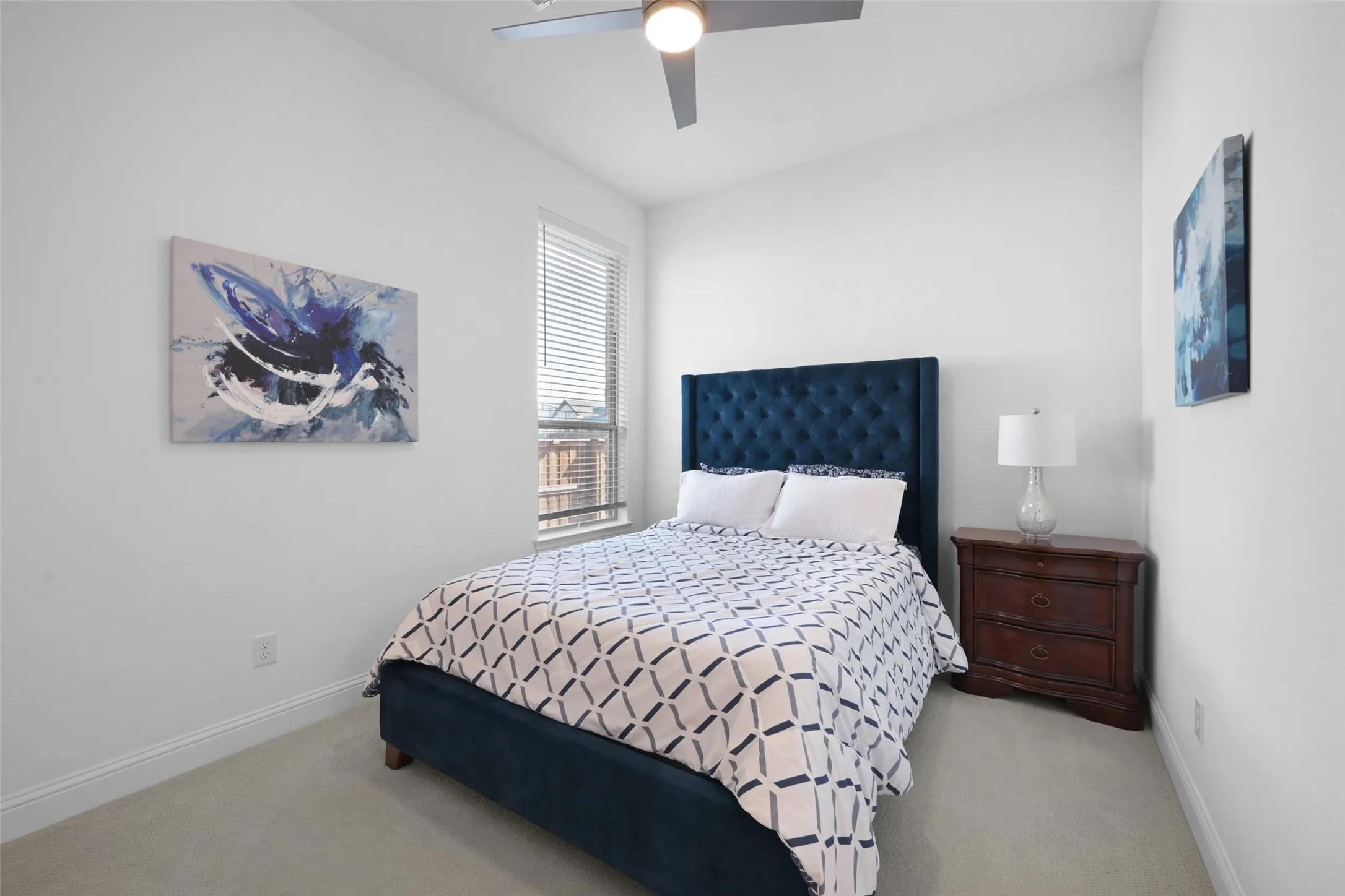 Bedroom featuring a window with horizontal blinds, a ceiling fan with integrated lighting, and neutral carpeting