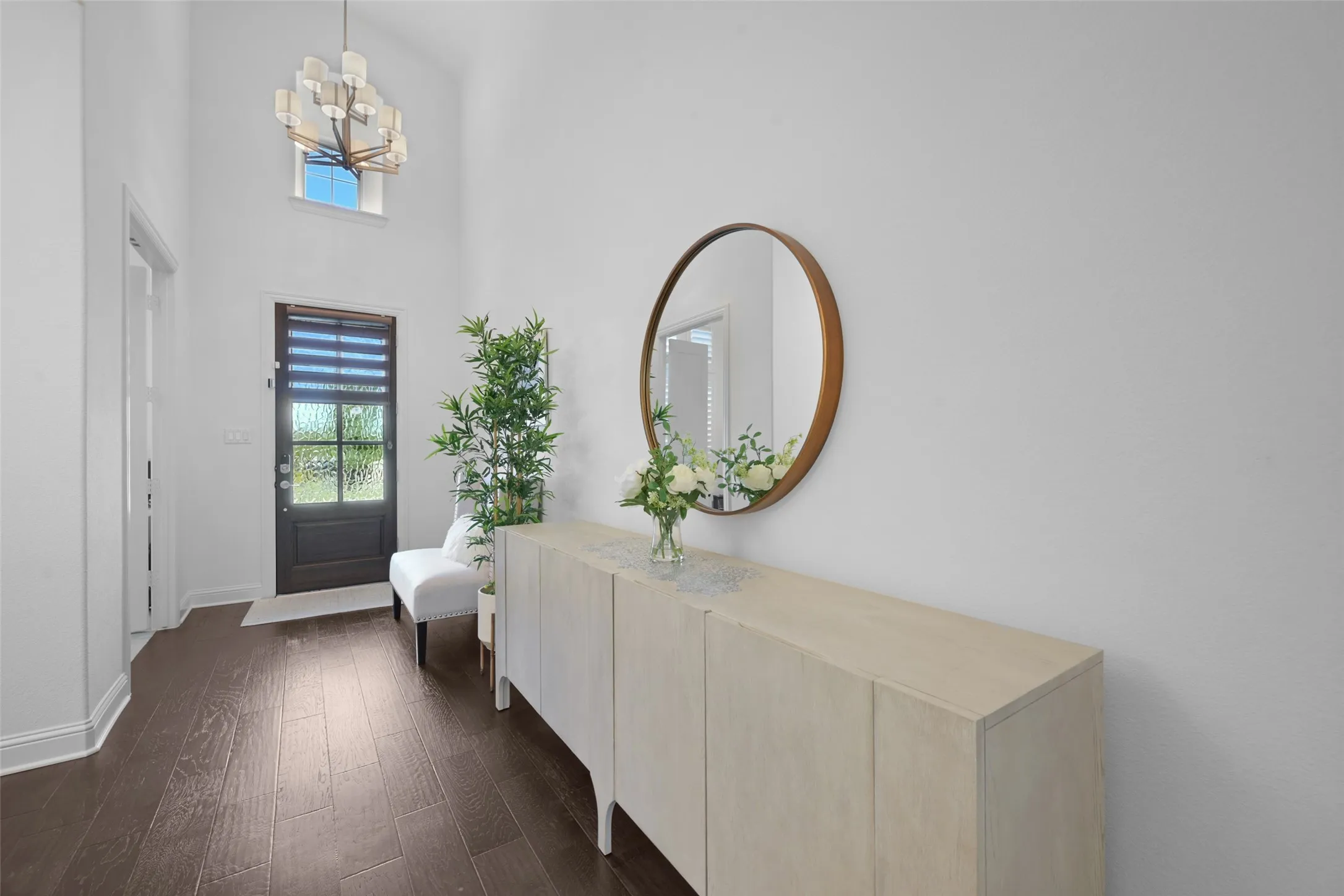 Foyer featuring wood-finish flooring, a contemporary chandelier, and a dark-paneled door with frosted glass
