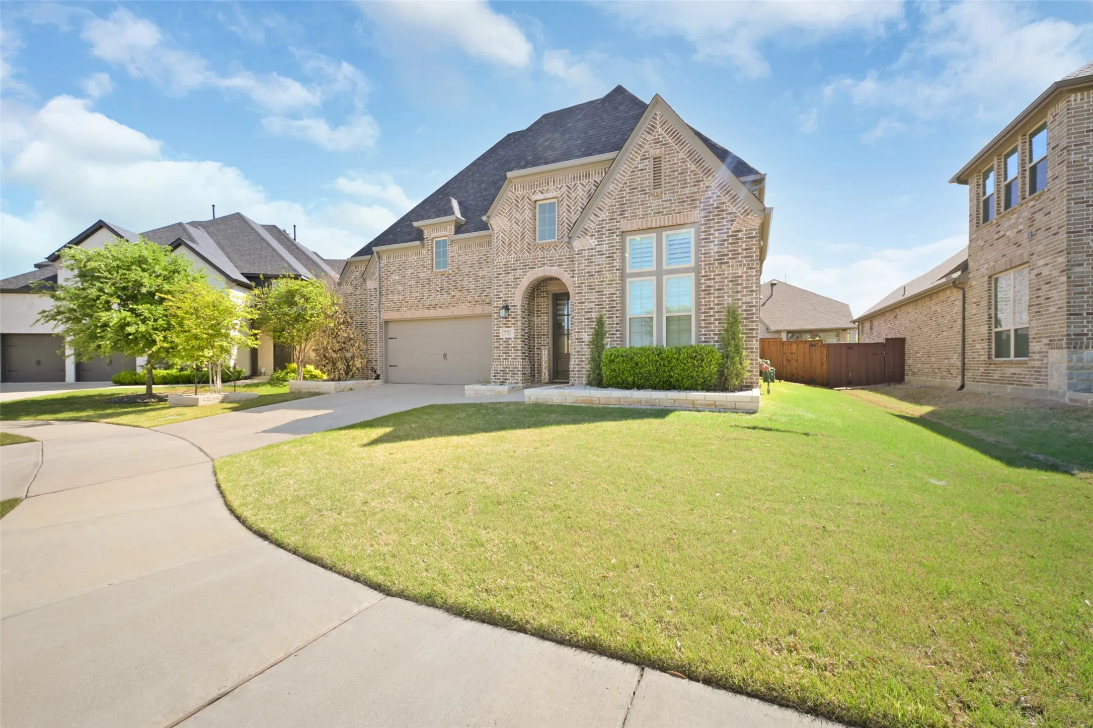 Two-story brick exterior with an arched entryway, gabled roofline, and attached garage