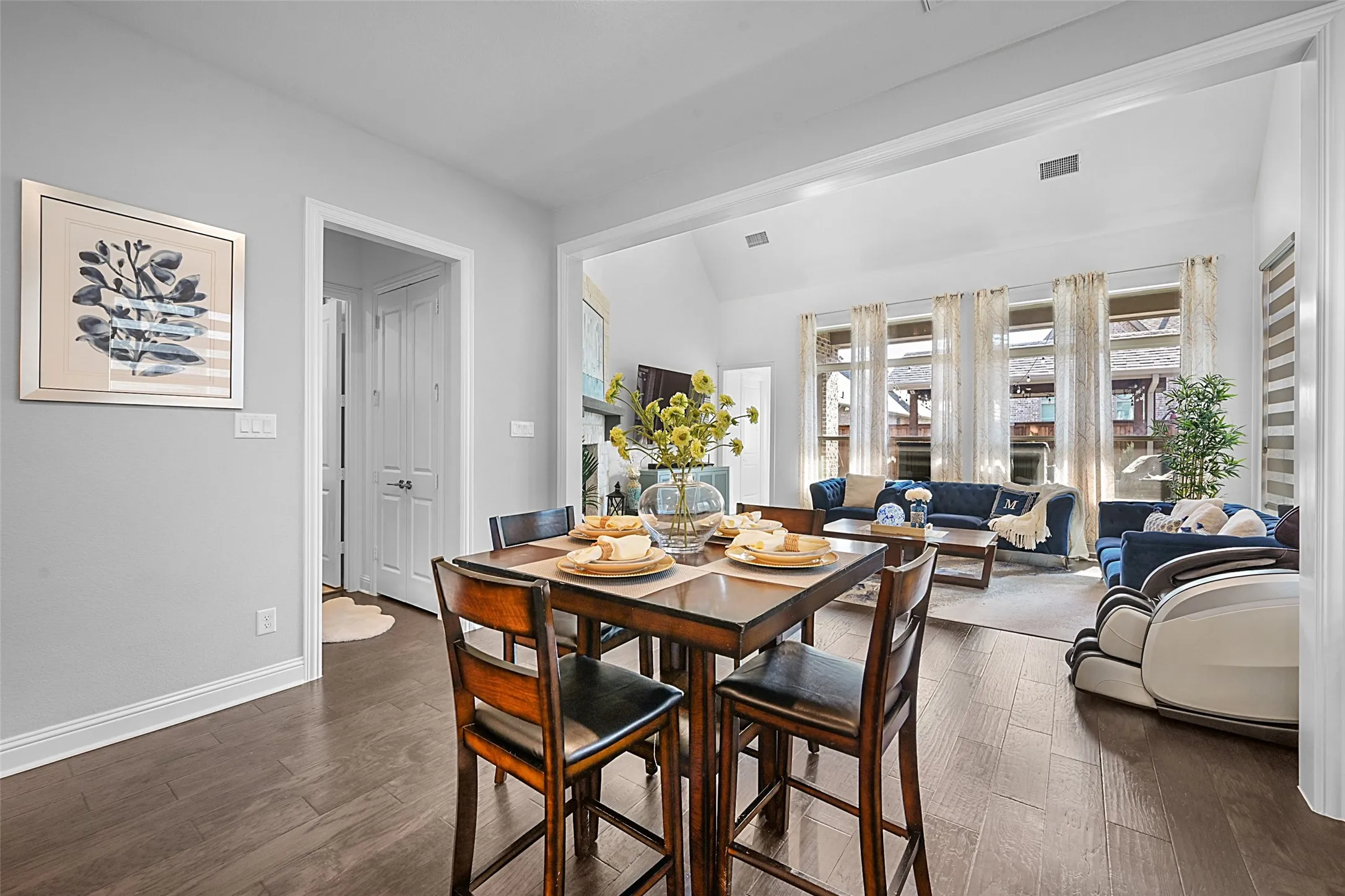 Open-concept interior featuring wood-finish flooring, a dining area, and a living area with multiple windows