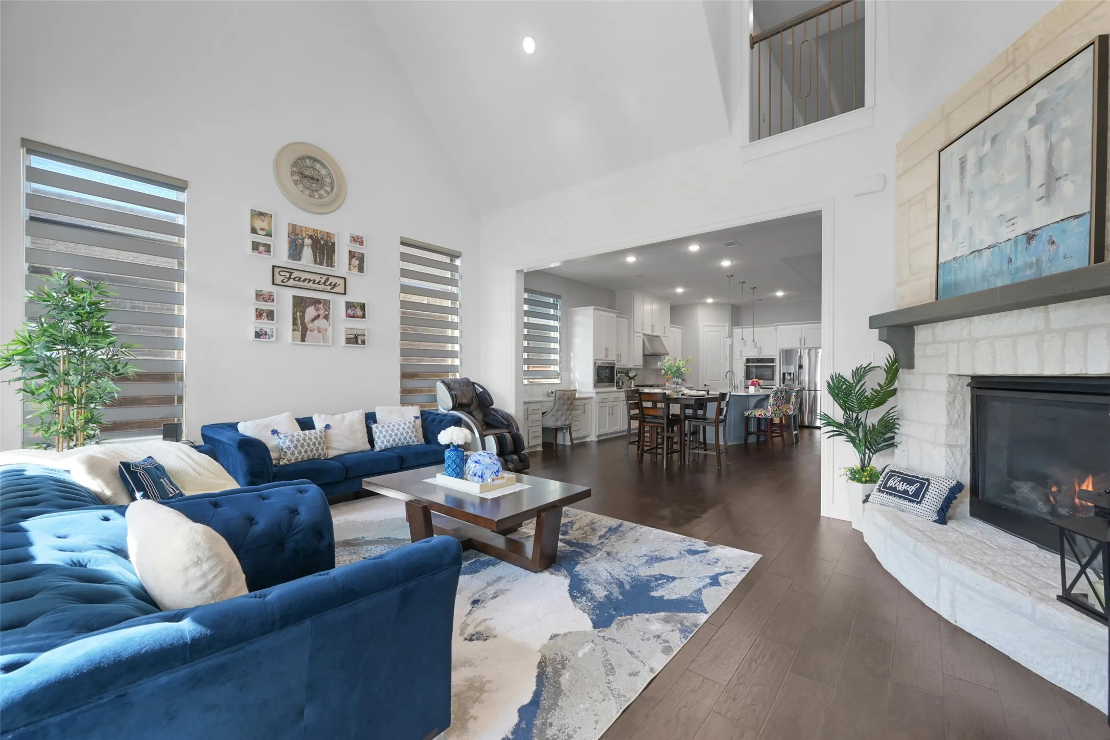 Living area featuring a vaulted ceiling, dark wood-finish flooring, and a white brick fireplace with a stone mantel