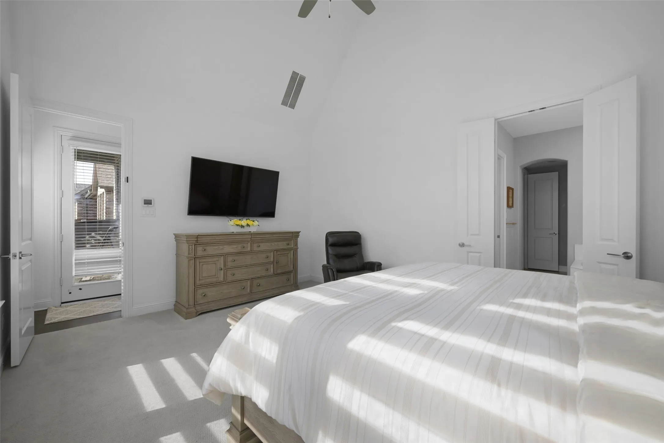 Bright room featuring vaulted ceilings, light carpeting, a transom window over the exterior door, and an arched doorway