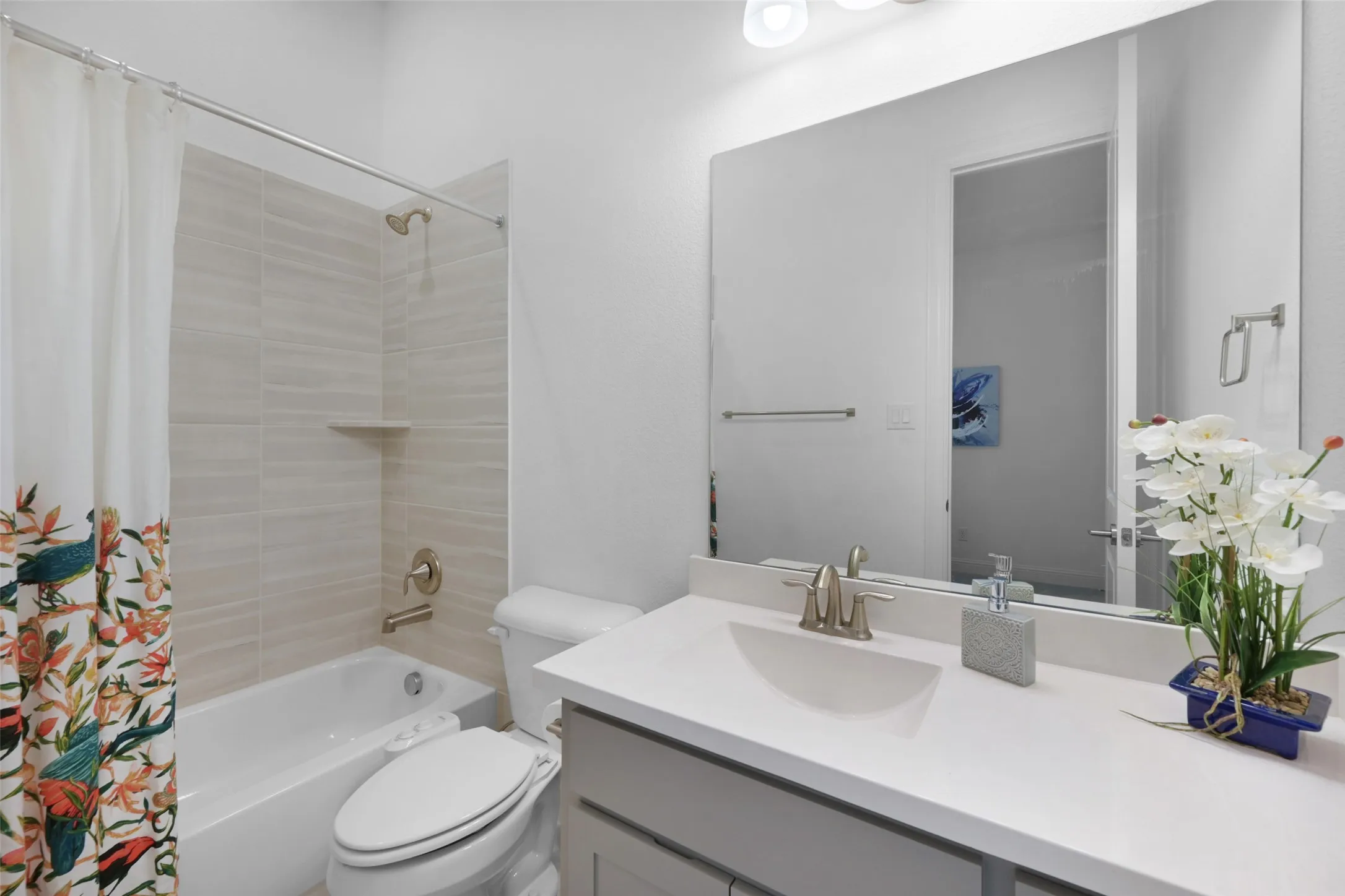 Bathroom featuring a white vanity with a rectangular undermount sink, brushed nickel faucet, and a large frameless mirror