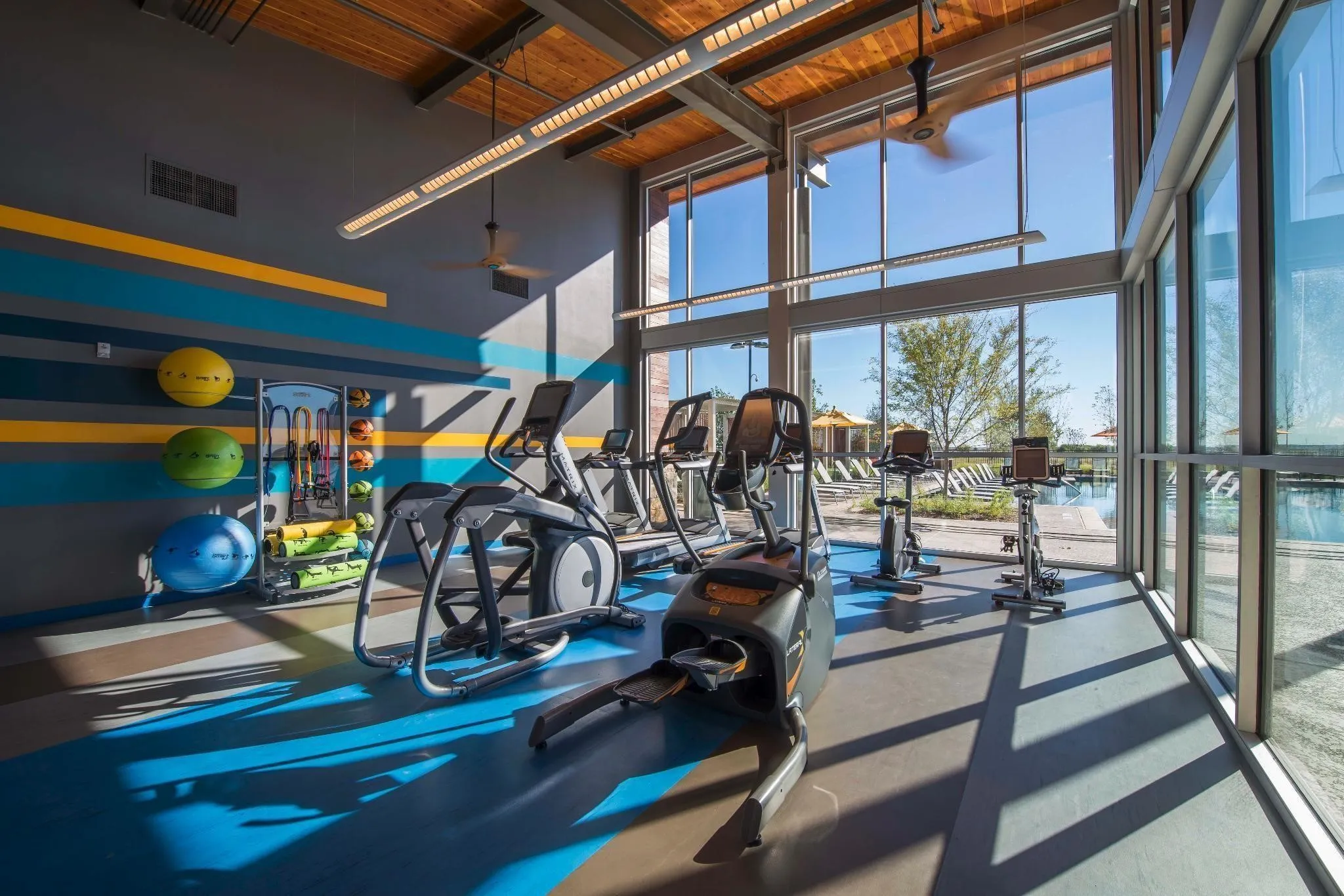 Spacious fitness center featuring high ceilings with exposed beams and wood-finish accents