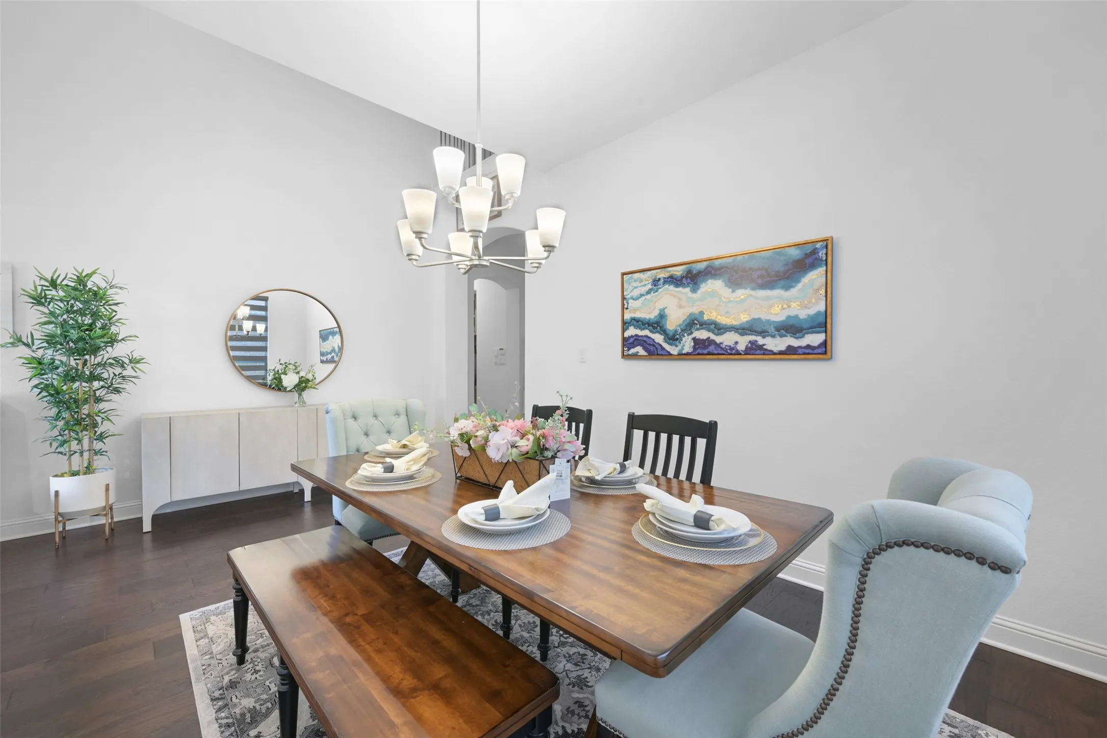 Dining area featuring a contemporary chandelier, vaulted ceiling, dark wood-finish flooring, and a decorative area rug