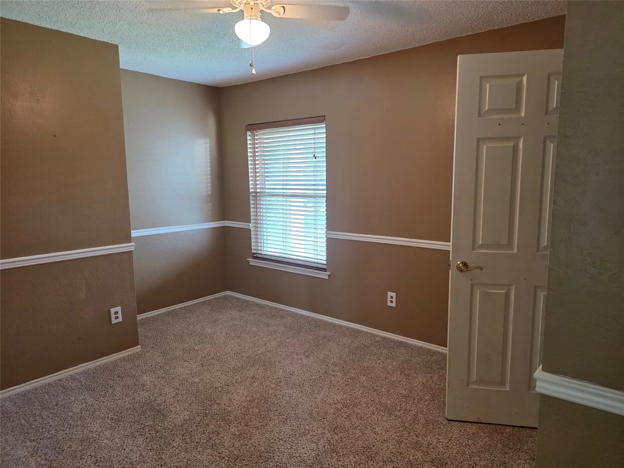 Carpeted room featuring a window with horizontal blinds, a ceiling fan with integrated lighting, and crown molding
