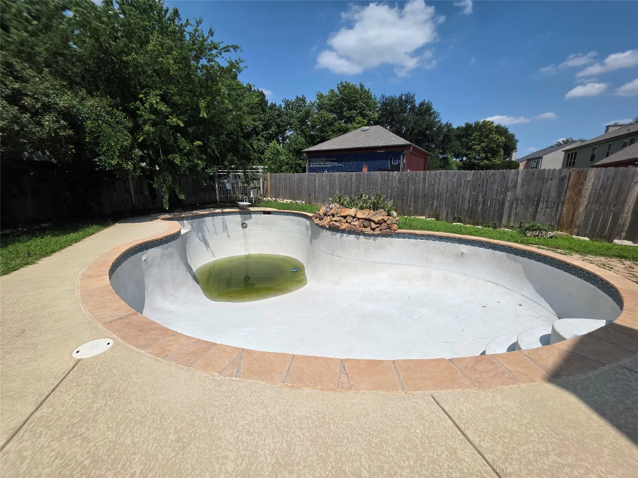In-ground pool featuring a stone coping border, integrated steps, and a decorative rock feature